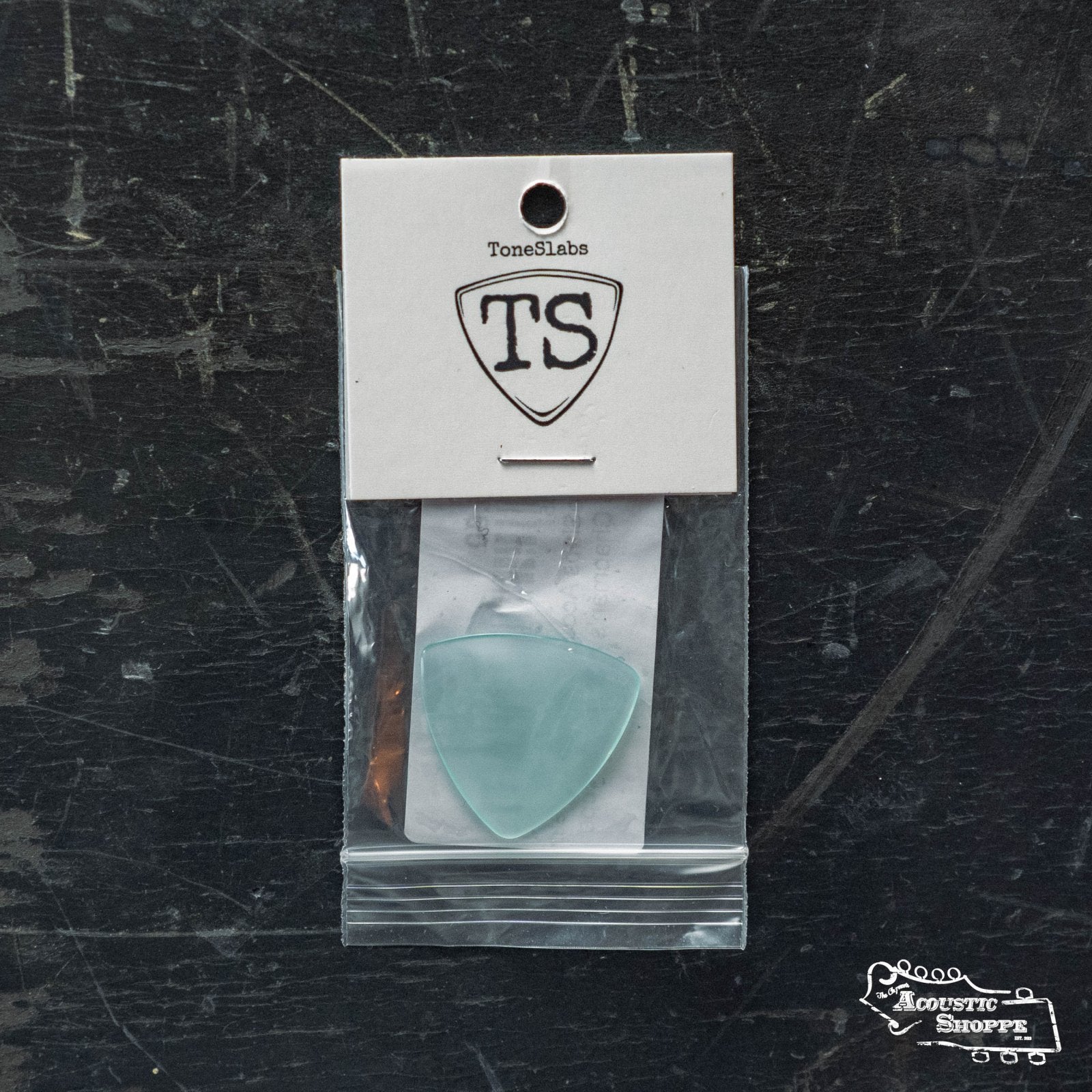 The ToneSlabs TAS Custom Mini Tri Guitar Pick - 1.3mm (Exclusive Color) by ToneSlabs is a translucent light blue pick, shown in a clear bag with the TS logo and Acoustic Shoppe branding—ideal for fans of premium acoustic accessories.