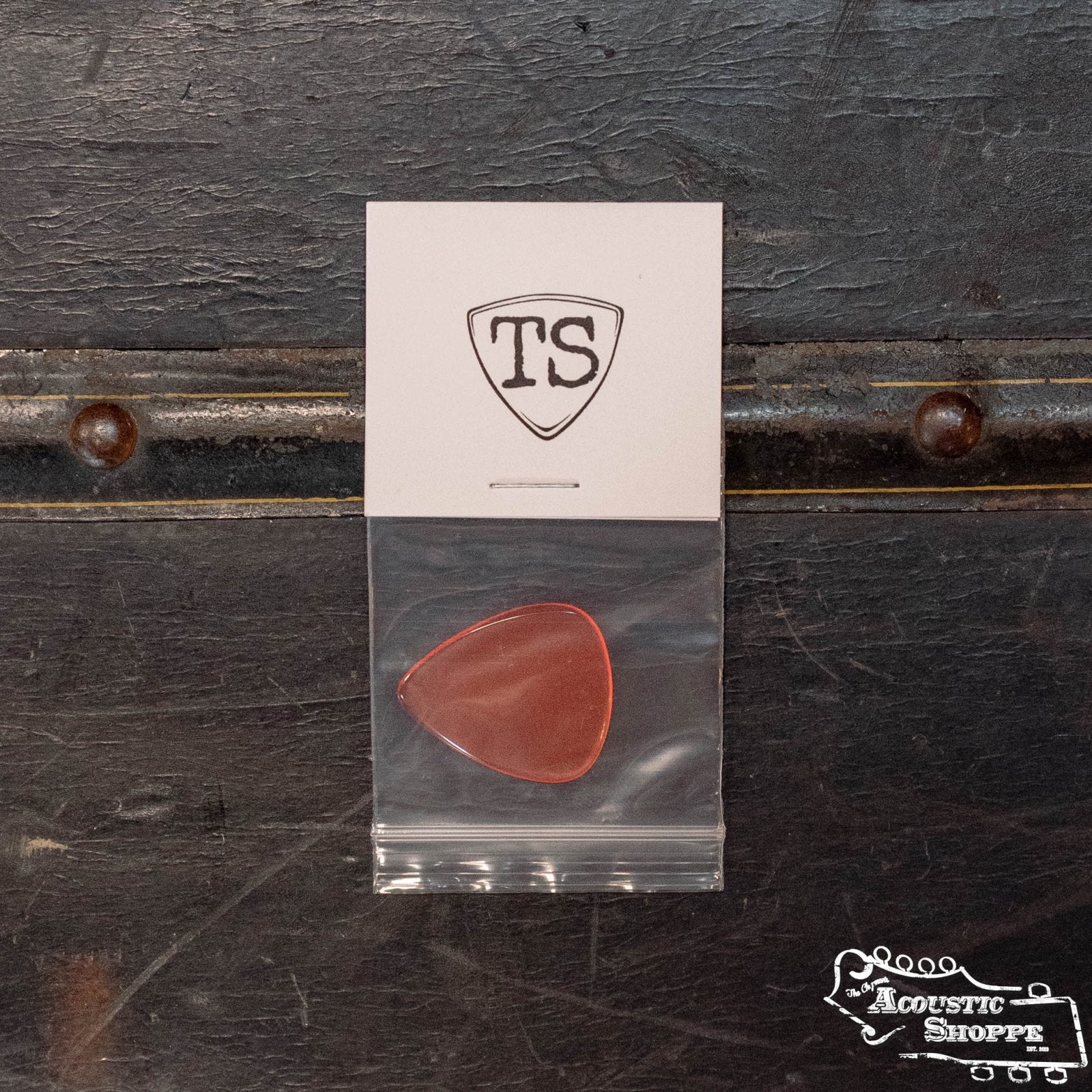 The ToneSlabs Tear Drop Guitar Pick - 1.2 mm comes in a clear bag on a white card featuring the TS logo. Shown on a dark textured surface with The Acoustic Shoppe logo, it's ideal for acoustic instrument accessories.