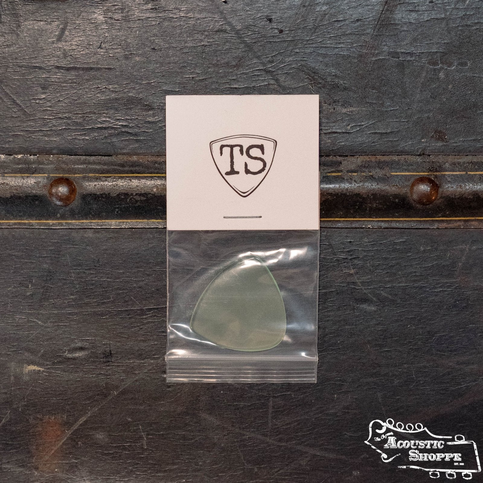 A ToneSlabs XL Tri Guitar Pick w/One Rounded Edge - 1.3 mm is shown in a small resealable bag on a dark surface, with a TS shield logo card above it and The Acoustic Shoppe logo in the bottom right corner.