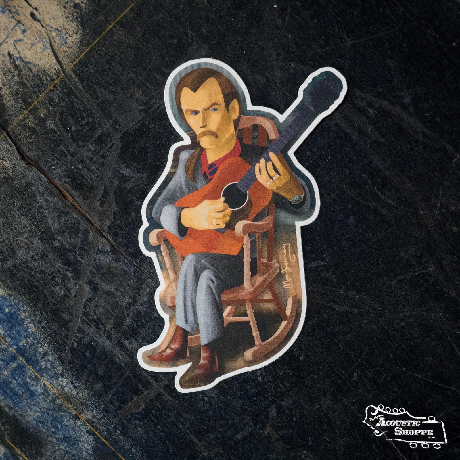 The Tony Rice Sticker by Mark A Montgomery from The Acoustic Shoppe features a serious cartoon man with a mustache, red vest, and gray outfit sitting in a worn wooden chair playing an acoustic guitar—ideal for boutique and acoustic fans.