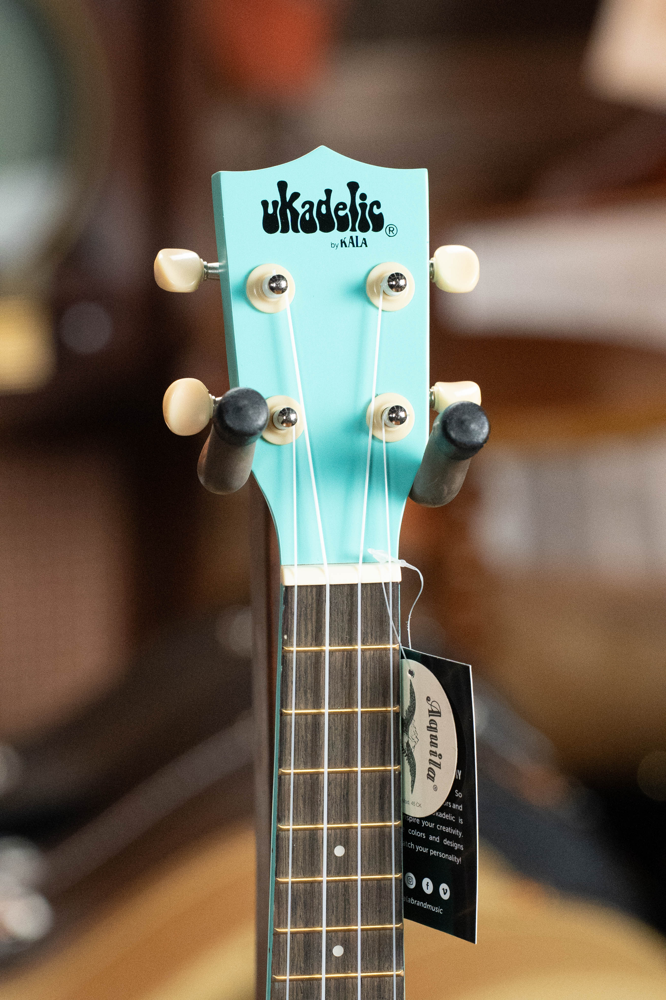 Aqua blue Kala Ukadelic Seascape soprano ukulele headstock with white tuning pegs and black strings. - Ukadelic Seascape Soprano Ukulele - Kala Brand - Default Title
