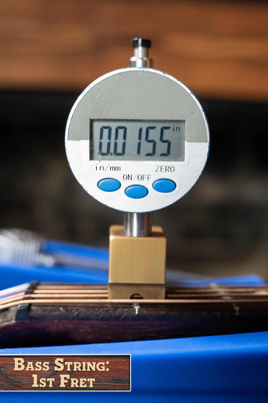 A digital gauge reads 0.0155 inches, measuring the bass string height at the 1st fret of a (Used) 1933 Gibson LOO Adirondack/Mahogany OO Tobacco Sunburst Acoustic Guitar #550 by Gibson, with a label: Bass String: 1st Fret.