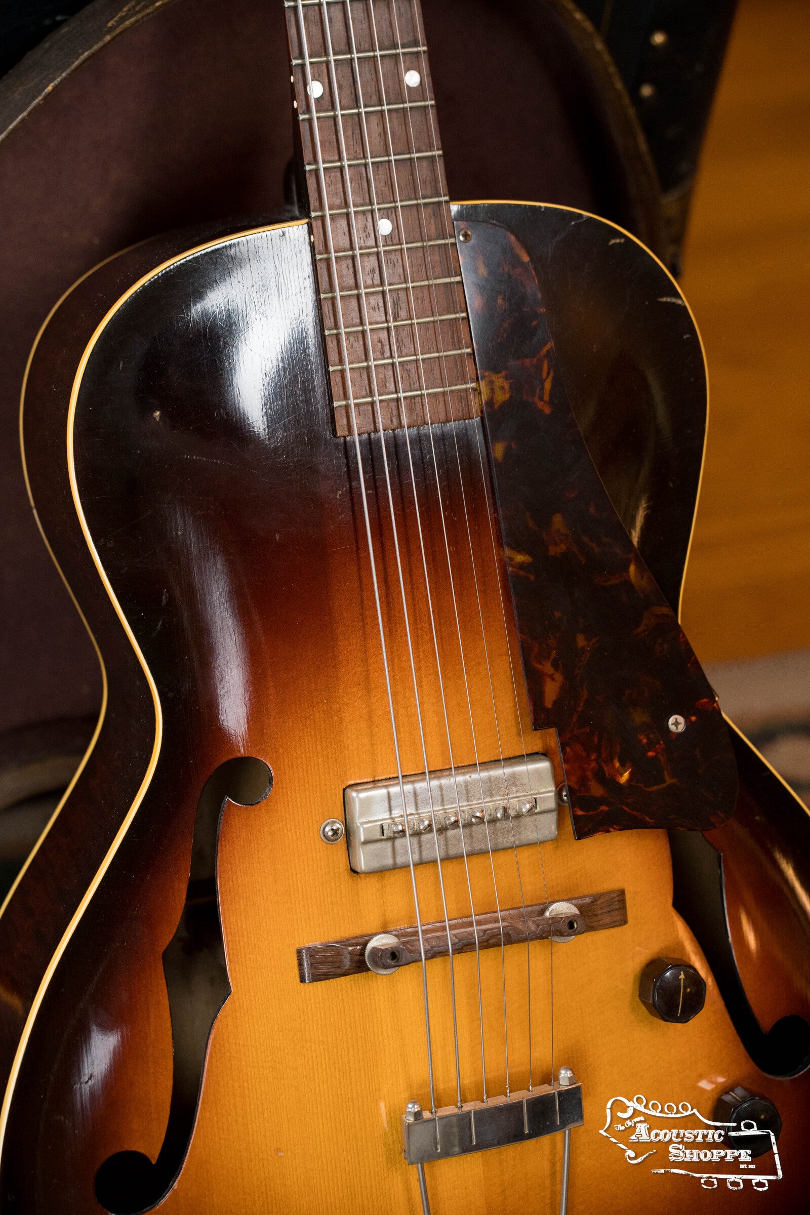 Close-up of a (Used) 1942 Gibson ES-125 hollow-body guitar by Gibson, featuring a sunburst finish, f-holes, classic P-90 pickup, and visible strings, bridge, pickguard, and neck in its open case.