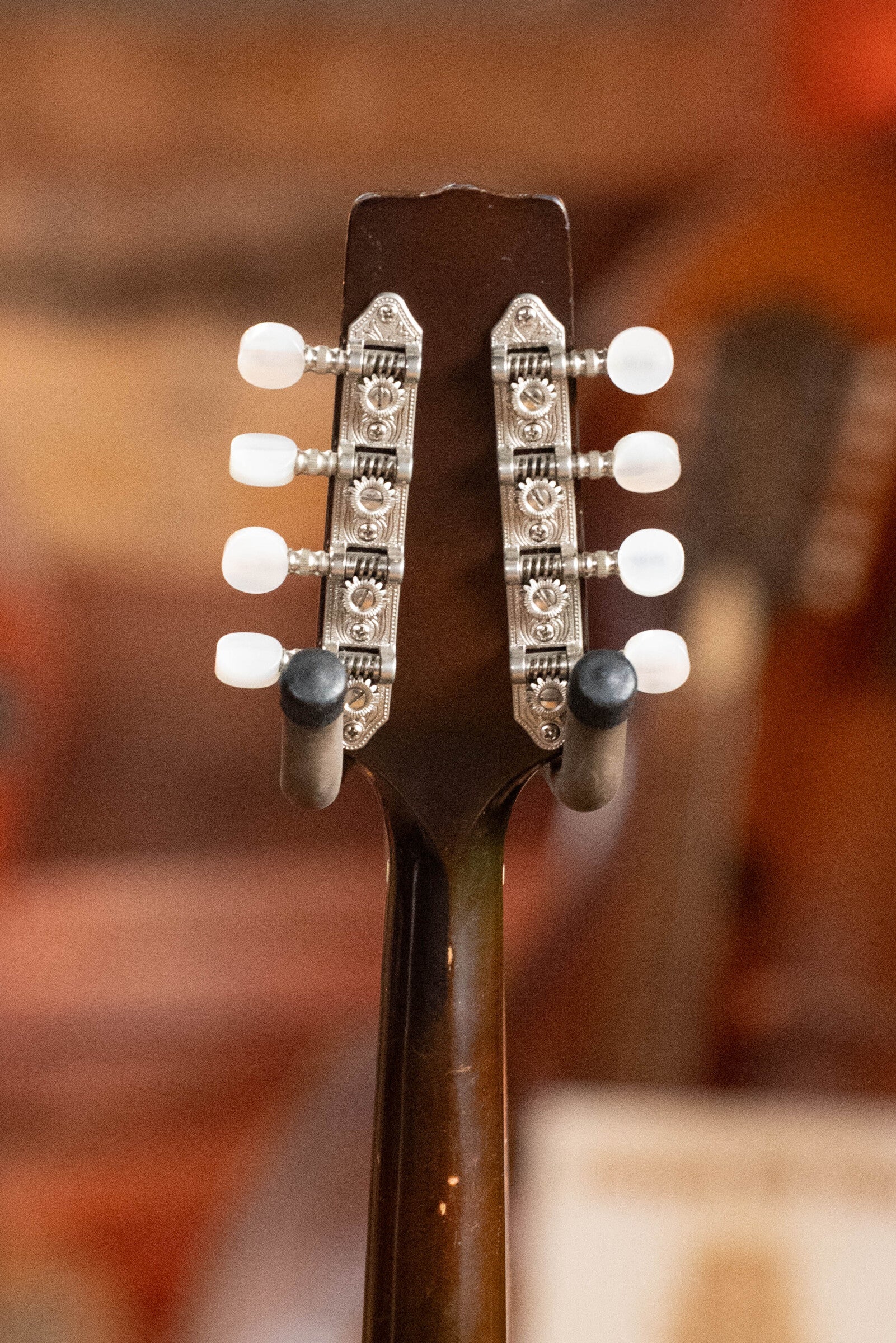 Close-up of the back of a (Used) 2003 Gibson Mastermodel A9 Spruce/Maple Mandolin #7040 headstock, featuring two rows of metal tuning pegs with white knobs on a dark neck—ideal for bluegrass players.