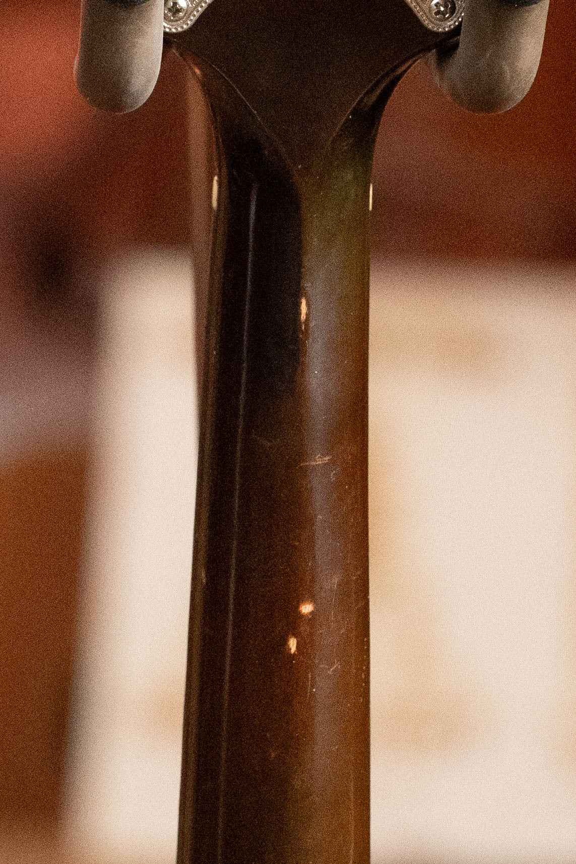 Close-up of the back of a (Used) 2003 Gibson Mastermodel A9 Spruce/Maple Mandolin #7040 headstock, showcasing its tuning pegs and neck. A softly blurred, warm-toned background completes this classic look for bluegrass fans.