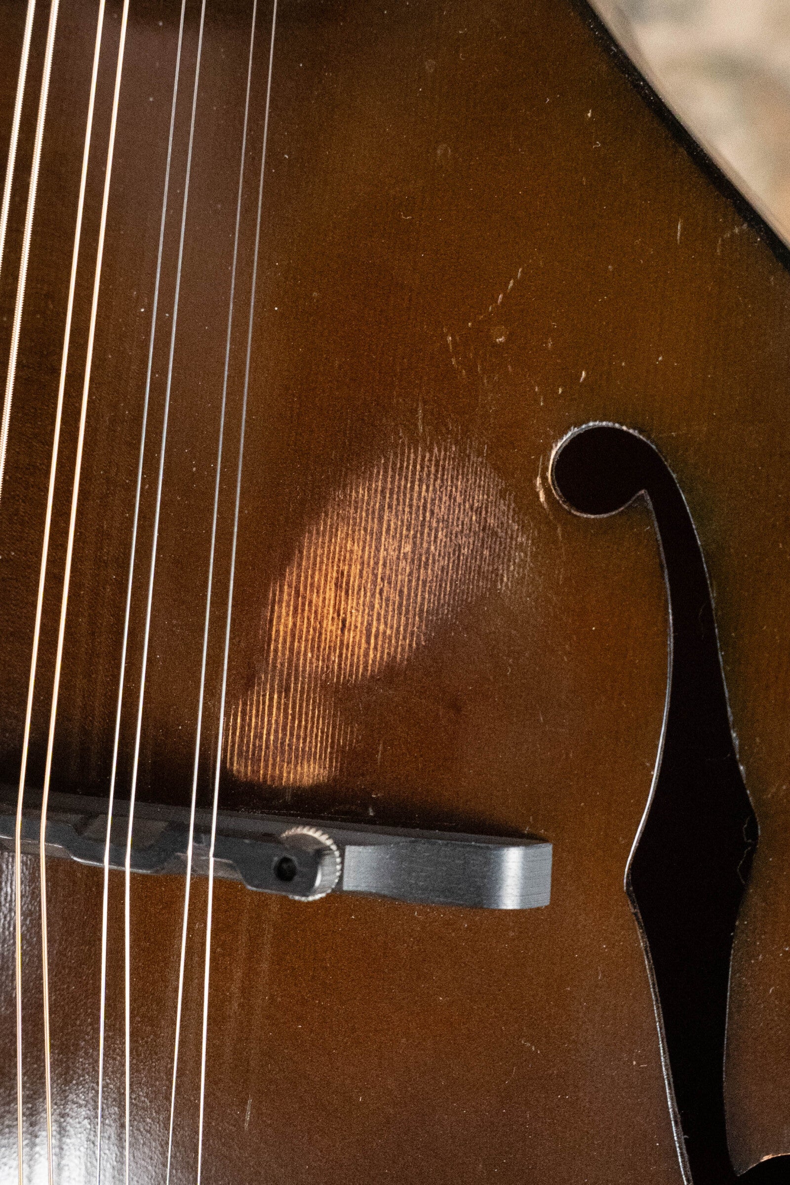 Close-up of a (Used) 2003 Gibson Mastermodel A9 Spruce/Maple Mandolin (#7040), highlighting its strings, bridge, f-hole, and a worn patch on the wooden body—classic Gibson details perfect for bluegrass music.