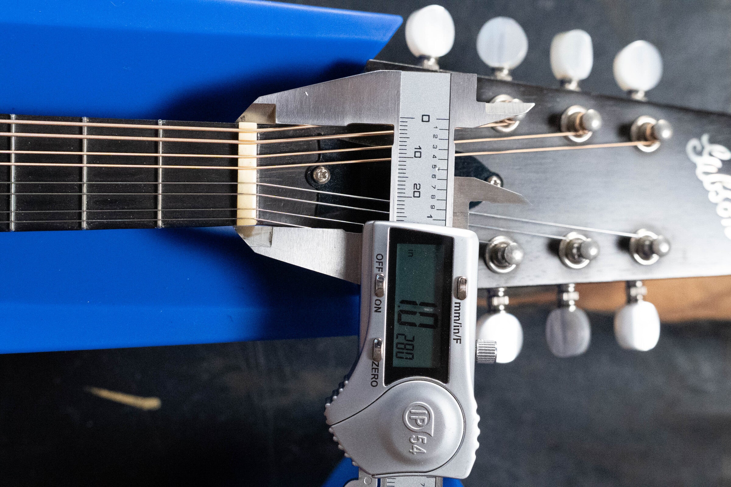 A digital caliper measures the neck width near the nut of this used 2003 Gibson Mastermodel A9 Spruce/Maple Mandolin (#7040) at 42.80 mm. The headstock, with white tuning pegs, shows partially visible Gibson branding.