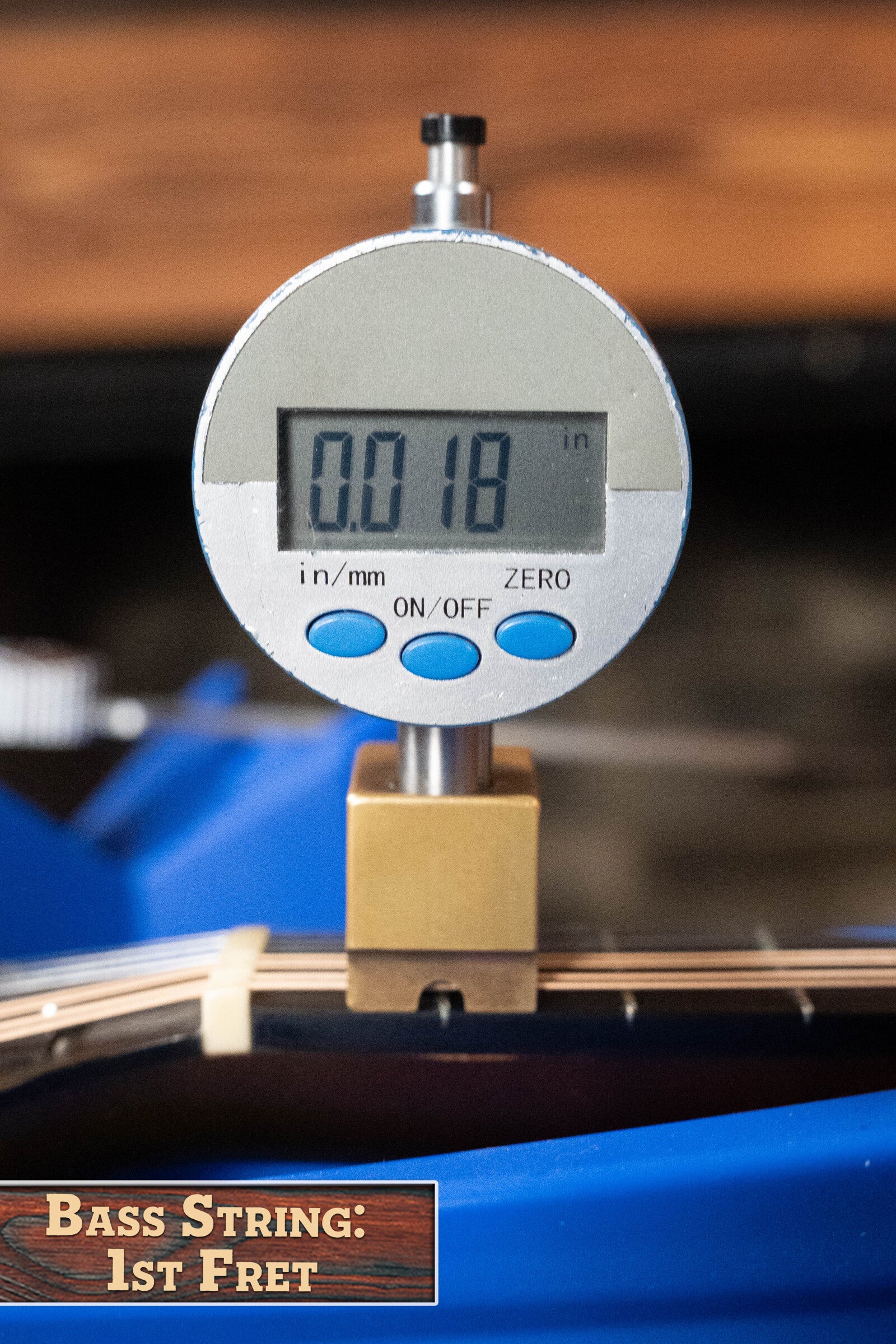A digital gauge reads 0.018 inches while measuring a bass guitar string at the first fret. The label says, “Bass String: 1st Fret,” next to a (Used) 2003 Gibson Mastermodel A9 Spruce/Maple Mandolin #7040 by Gibson.