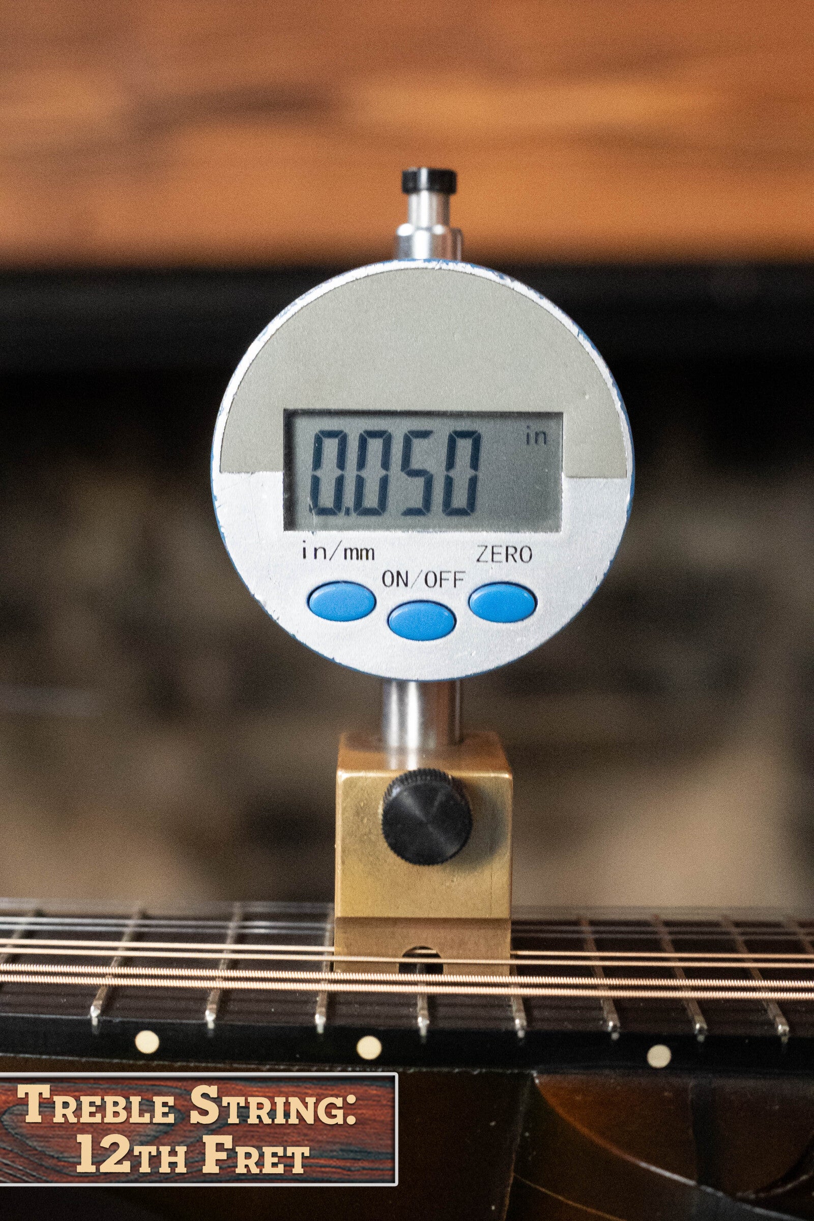 A digital gauge shows 0.050 at the 12th fret, ideal for setting up your (Used) 2003 Gibson Mastermodel A9 Spruce/Maple Mandolin #7040 for crisp bluegrass tones.