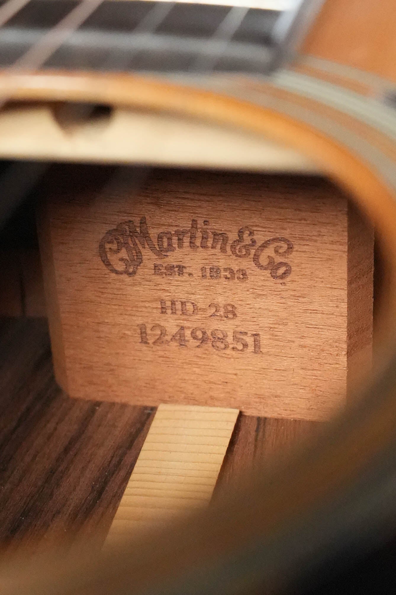 Close-up inside a (Used) 2007 Martin HD-28 Solid Sitka Spruce/East Indian Rosewood Dreadnought by Martin & Co., showing the logo and serial number #9851 stamped on the interior wood brace.