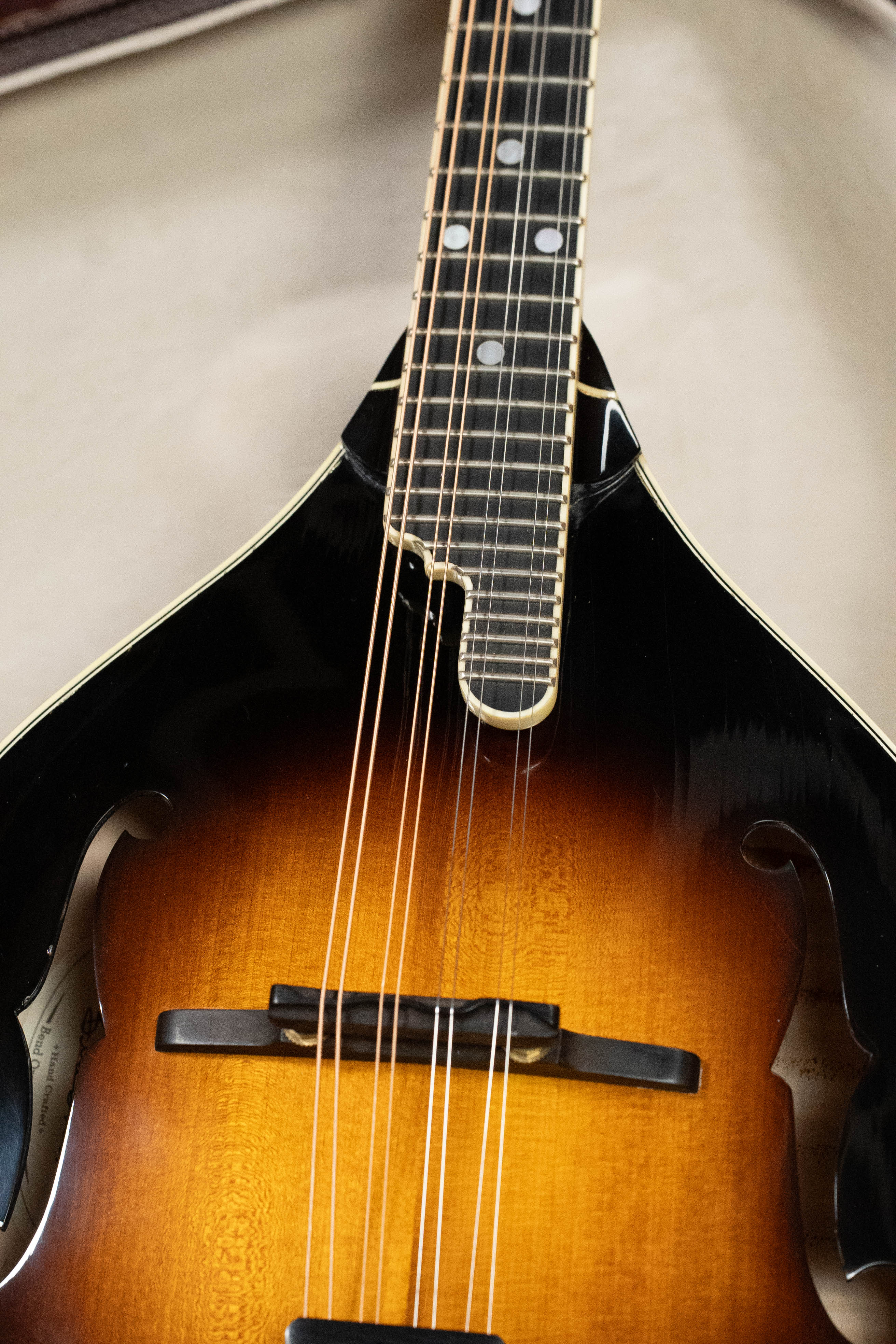Close-up of a used 2016 Weber Fern A-style mandolin (#2801) with red spruce top, flamed maple back, sunburst finish, f-holes, eight strings, and a notched fingerboard by Weber, shown against a plain light background.