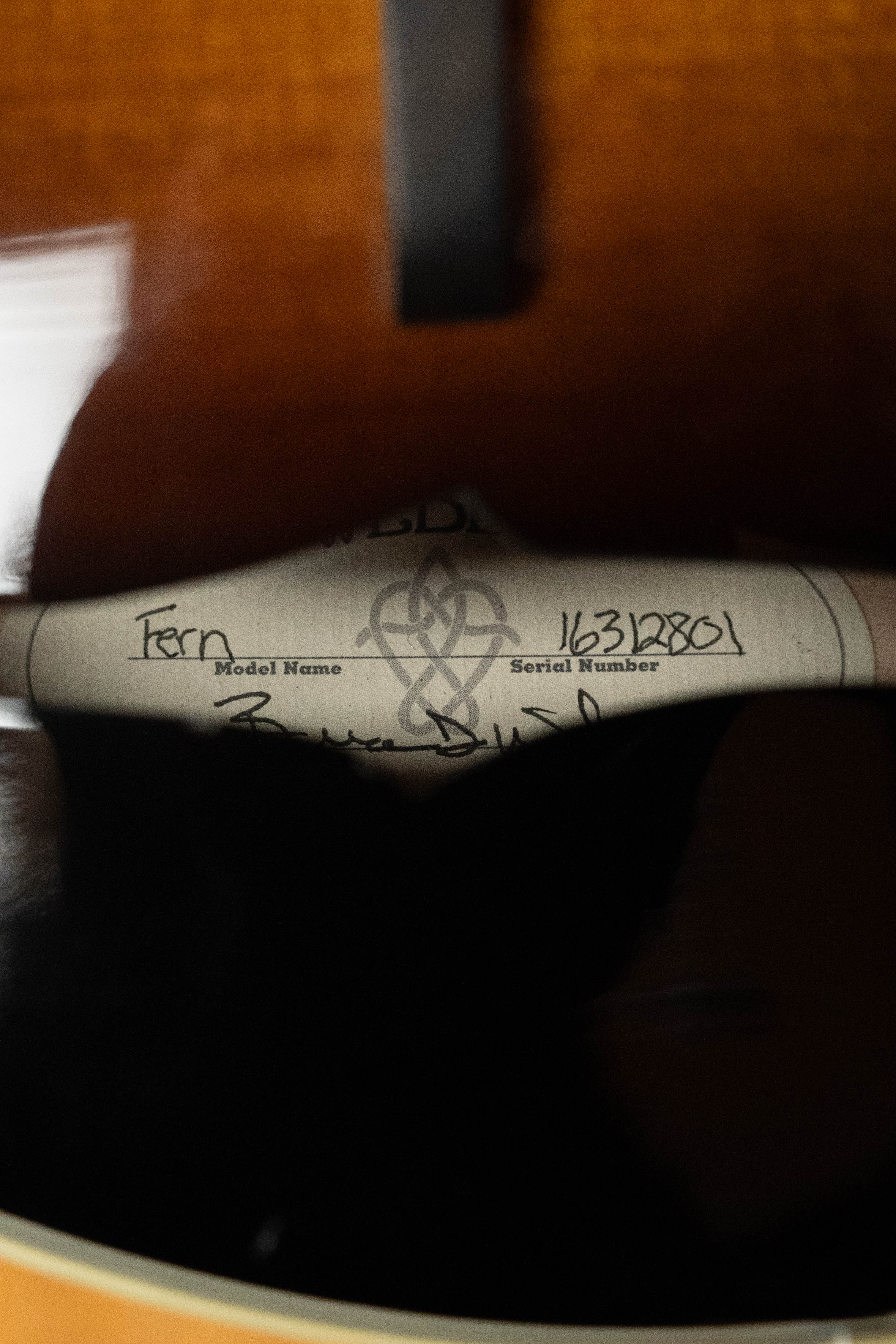 Close-up of a Weber A-style mandolin’s soundhole shows the paper label inside with handwritten model “Fern” and serial “#2801” beneath the logo. The red spruce top finish frames the label on this 2016 used Weber Fern mandolin.