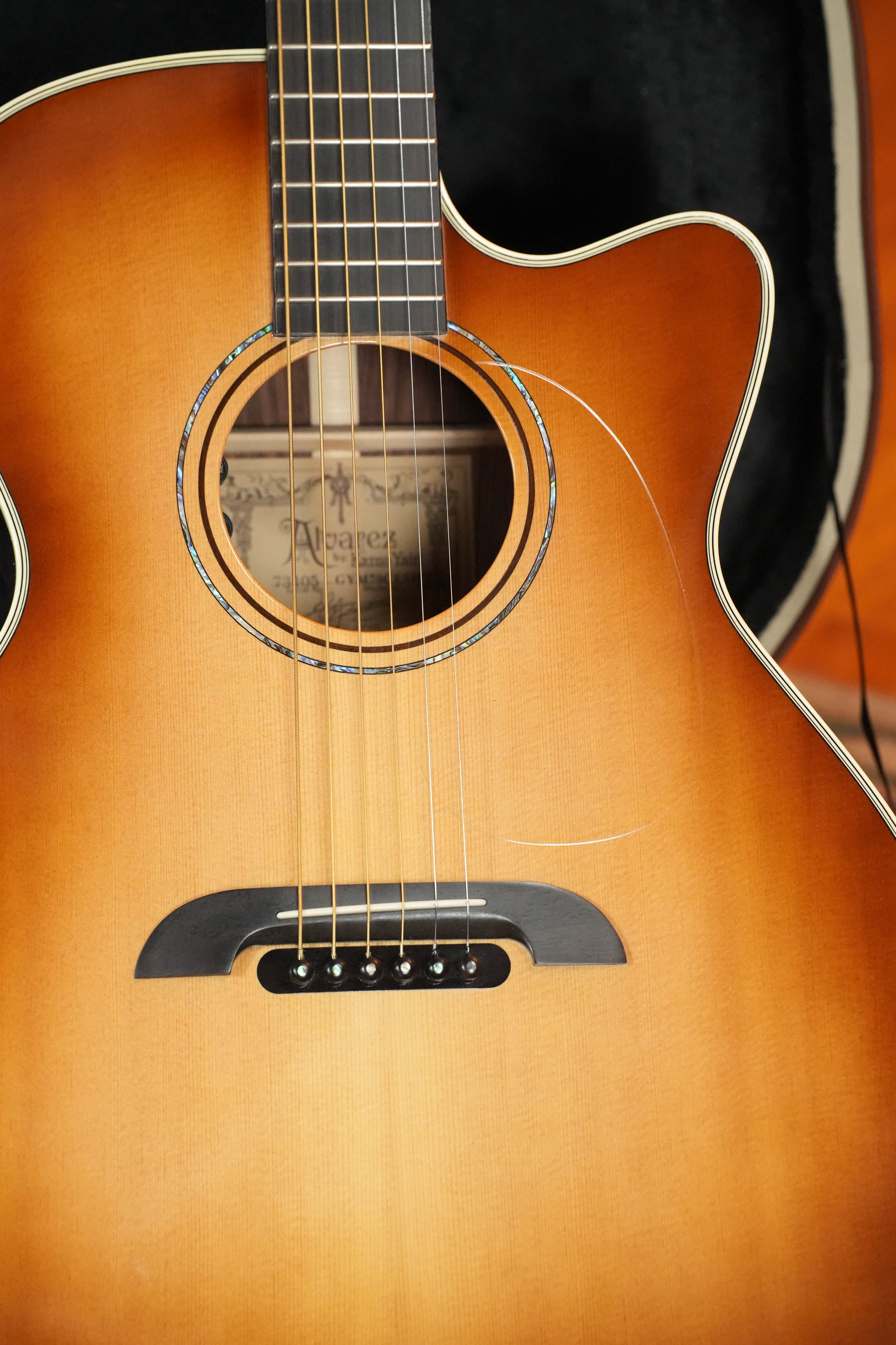 A close-up of a (Used) 2018 Alvarez Yairi GYM70CESHB Grand Auditorium acoustic guitar from The Acoustic Shoppe shows the strings, sound hole, and glossy sunburst finish, with the brand label visible inside this handmade Japanese guitar.