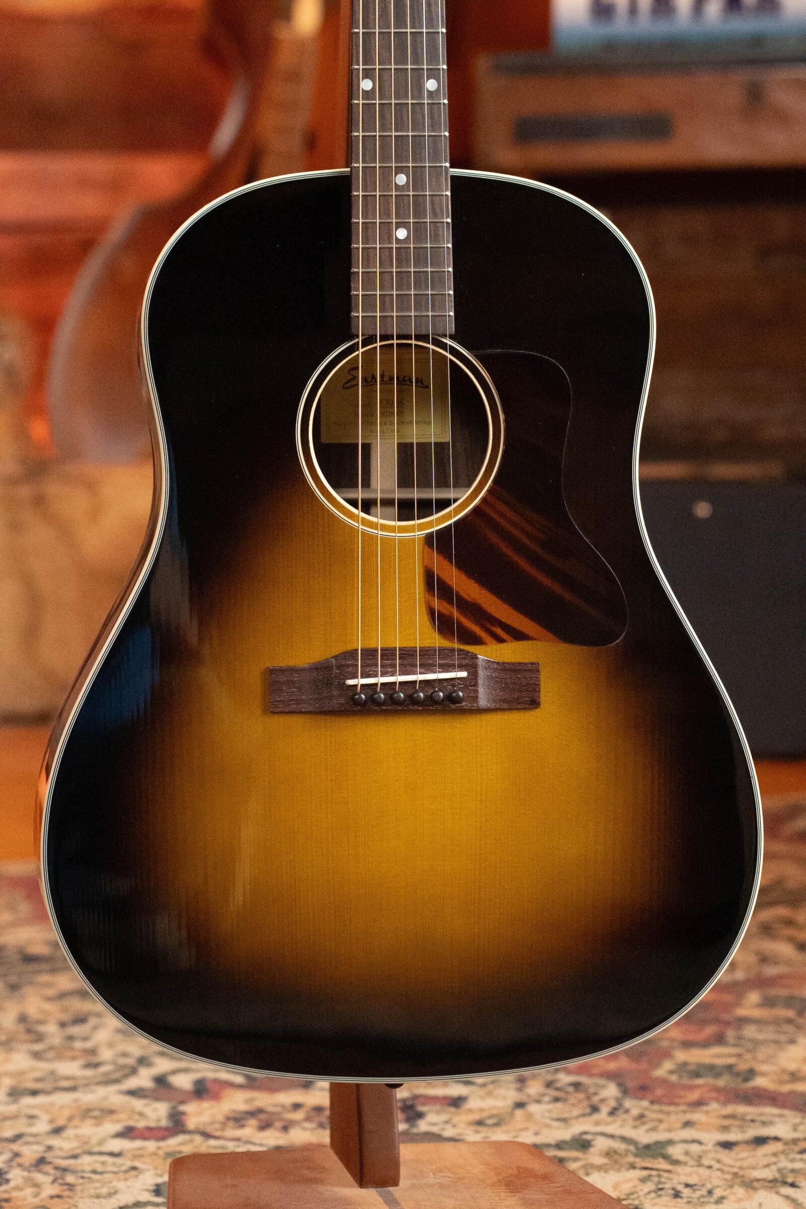 A used 2021 Eastman Guitars E20SS Adirondack/Rosewood Slope Shoulder Dreadnought (#6671) is displayed upright on a wooden stand in a cozy, wood-paneled room.