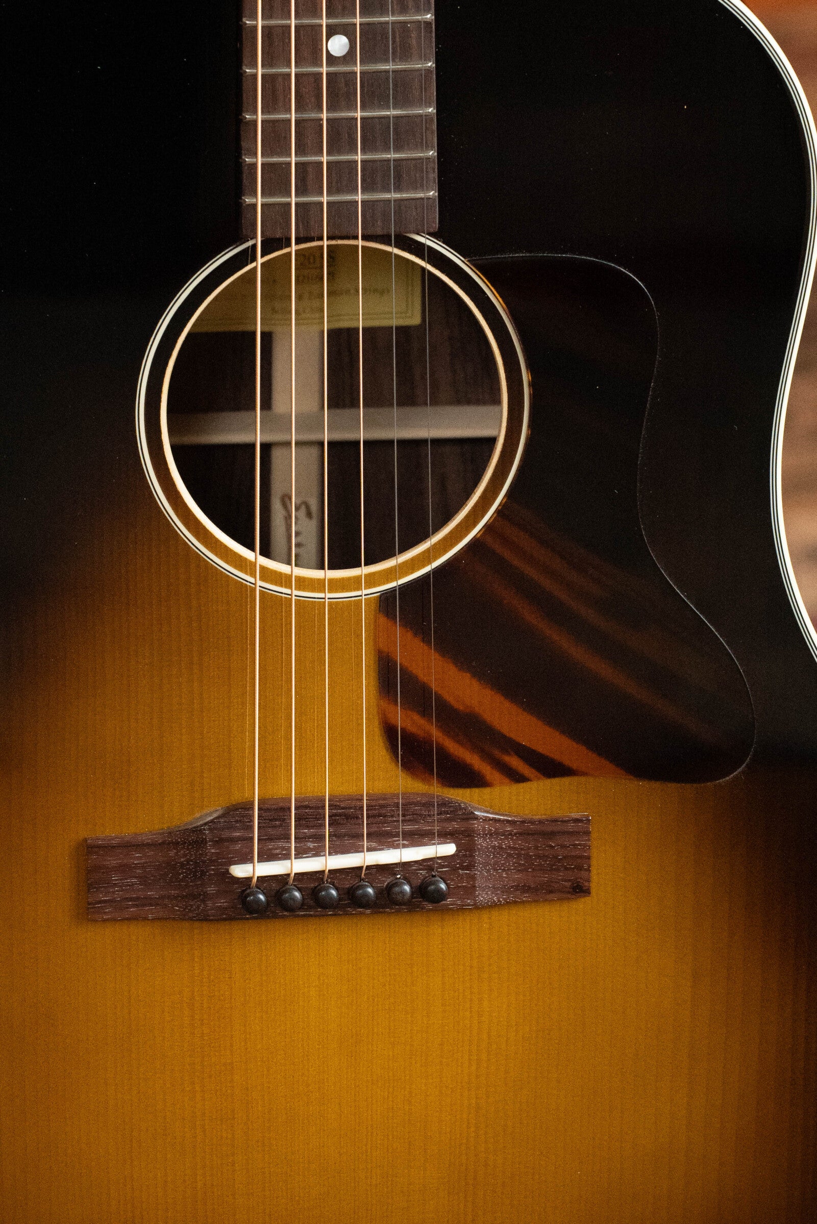 A close-up of a Used 2021 Eastman Guitars E20SS Adirondack/Rosewood Slope Shoulder Dreadnought Acoustic Guitar #6671 highlights its solid Adirondack spruce top, strings, sound hole, bridge, pickguard, neck, and sunburst finish in brown and yellow tones.
