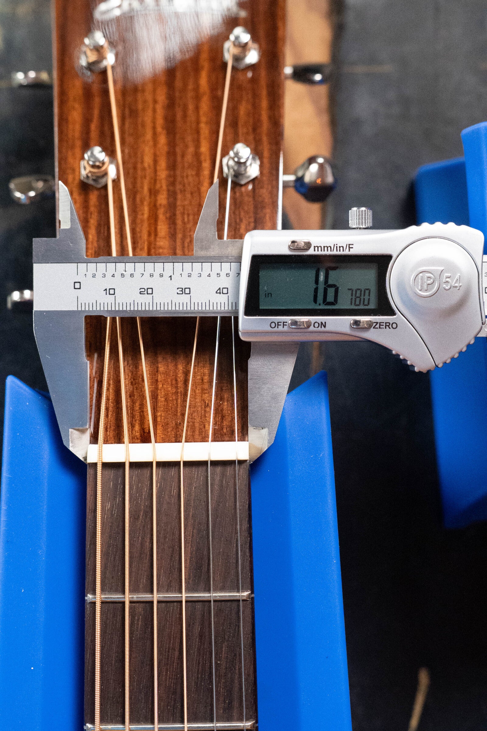 A digital caliper measures the nut width of a (Used) 2021 Eastman E20SS Adirondack/Rosewood Slope Shoulder Dreadnought Acoustic Guitar #6671 by Eastman Guitars at 1.6780 inches, with blue supports holding it in place.