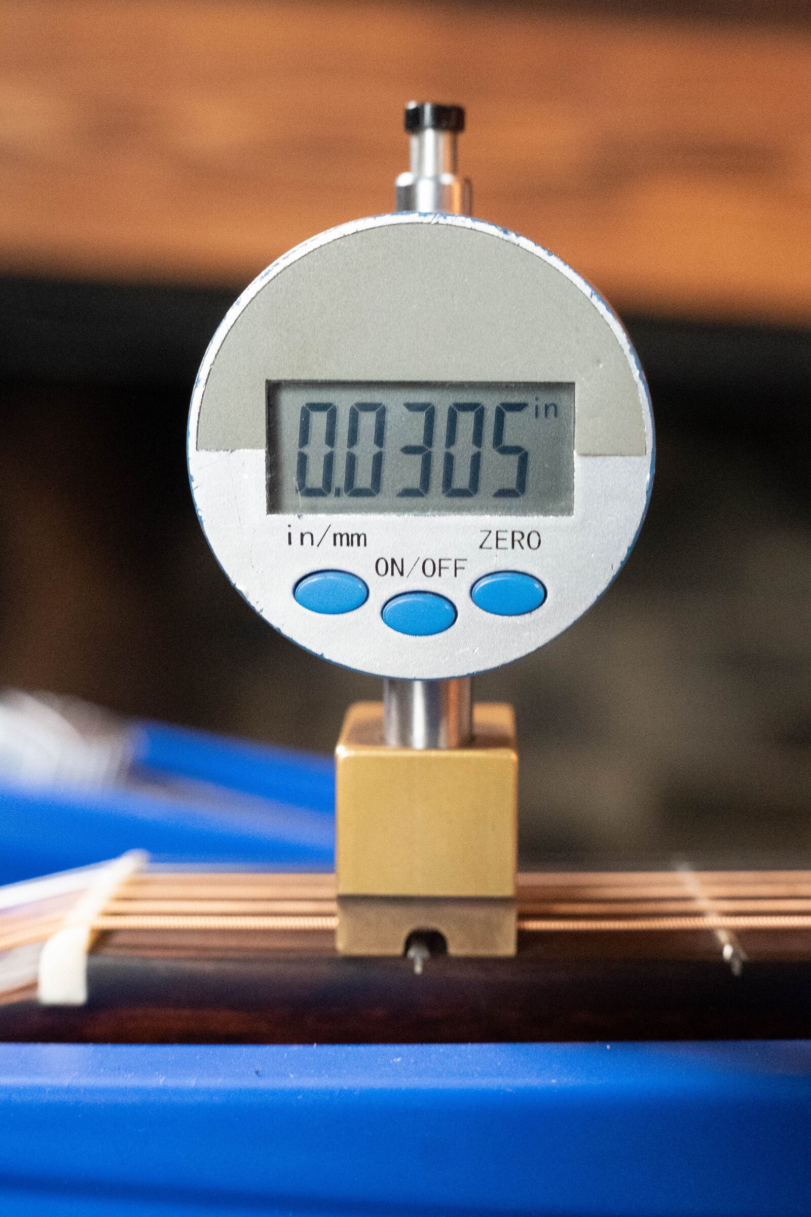 A digital caliper shows 0.0305 inches while measuring string height above the fretboard of a (Used) 2021 Eastman E20SS Adirondack/Rosewood Slope Shoulder Dreadnought Acoustic Guitar #6671 by Eastman Guitars. Blue and white wires appear in the background.