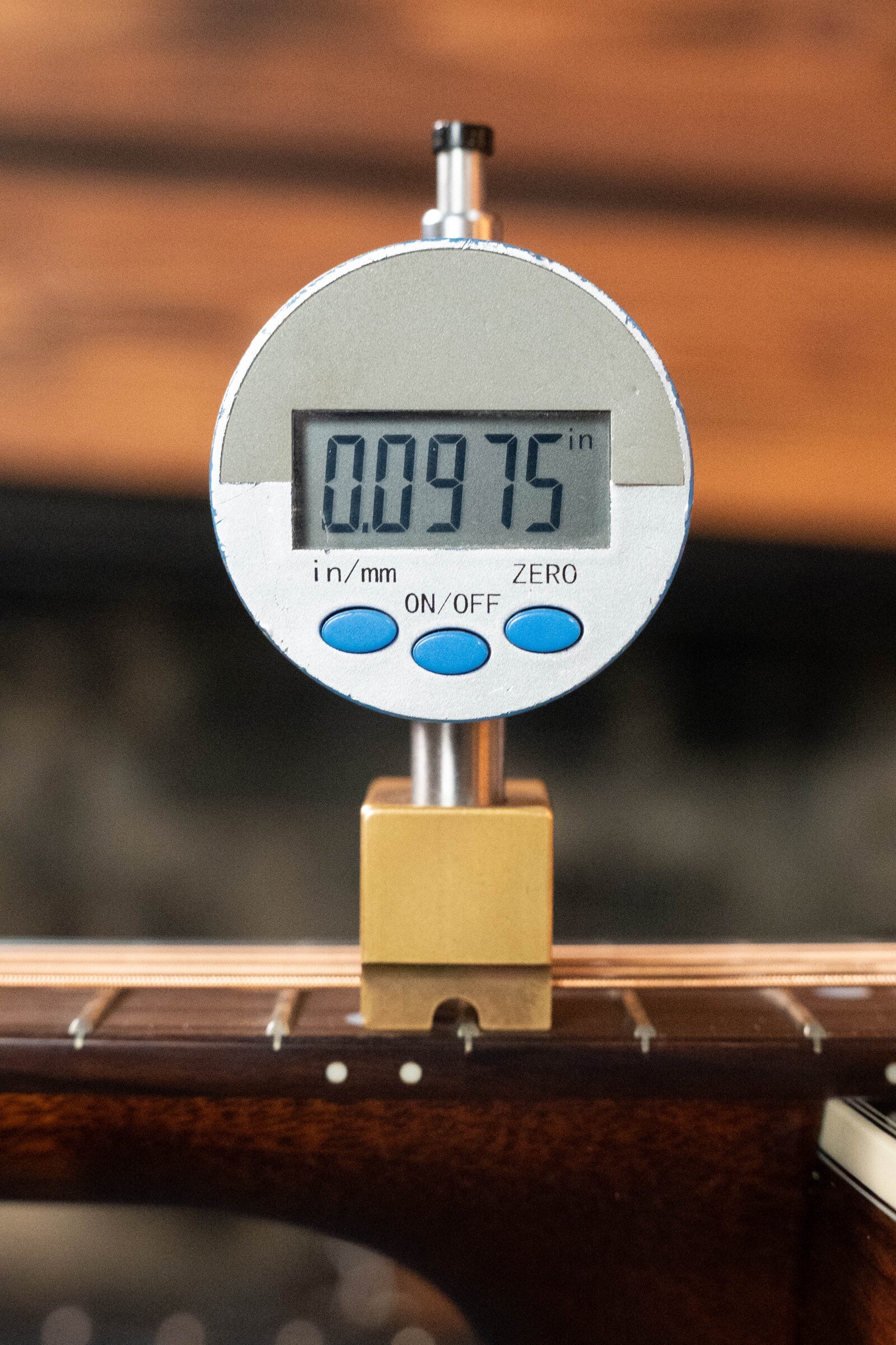 A digital caliper reads 0.0975 inches for the string action above the frets and Adirondack spruce top of a (Used) 2021 Eastman E20SS Slope Shoulder Dreadnought Acoustic Guitar #6671 by Eastman Guitars.