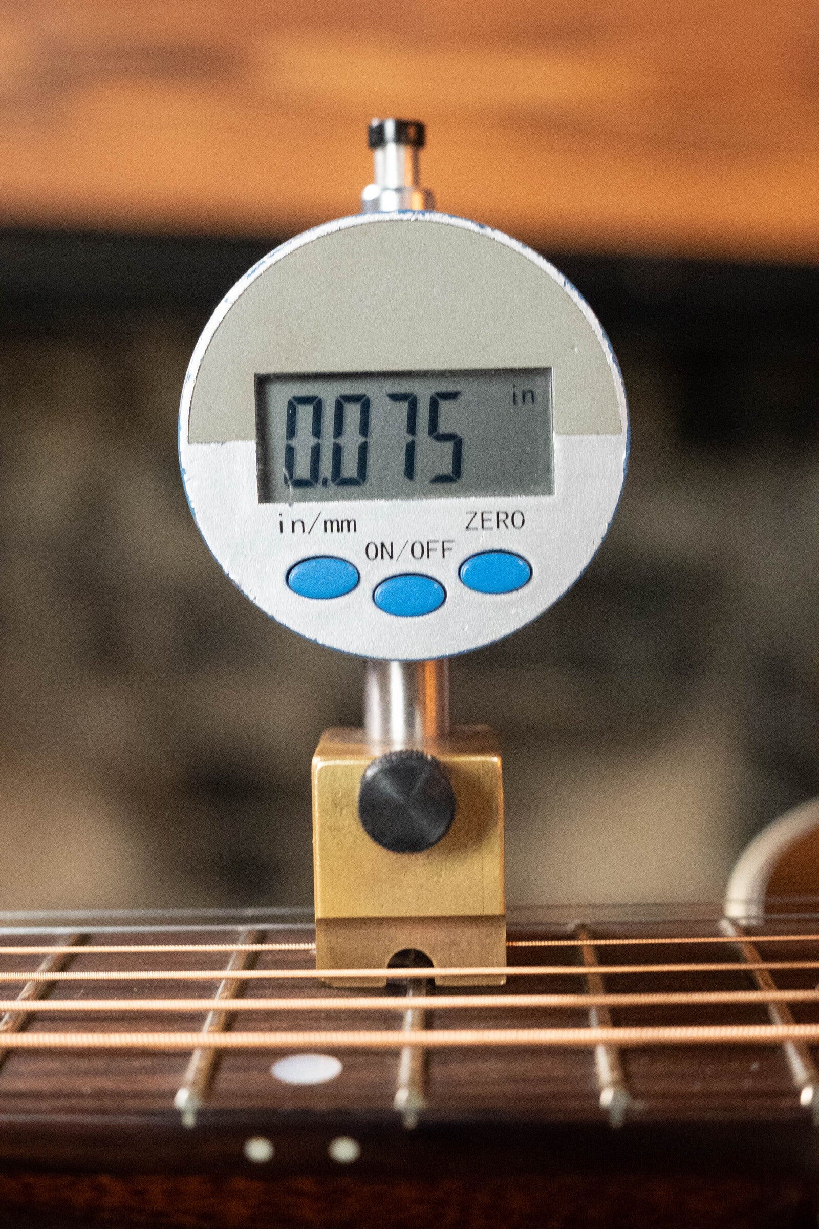 A digital gauge reads 0.075 inches, measuring the string height above the fretboard on a (Used) 2021 Eastman E20SS Adirondack/Rosewood Slope Shoulder Dreadnought Acoustic Guitar #6671 by Eastman Guitars.