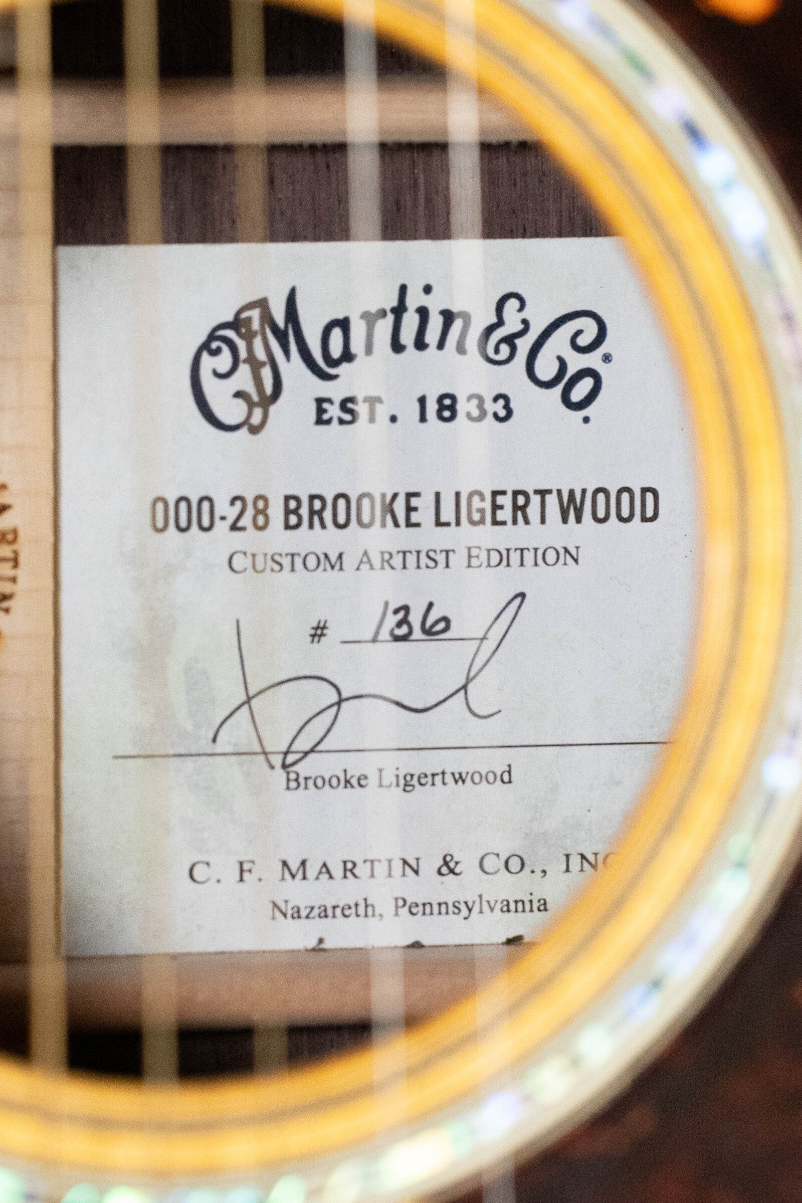 Close-up of a (Used) 2022 Martin Brook Ligertwood 000-28 Spruce/Rosewood OOO Acoustic Guitar label, signed by Brooke Ligertwood. Features East Indian rosewood and bears the Martin & Co. logo from Nazareth, Pennsylvania.
