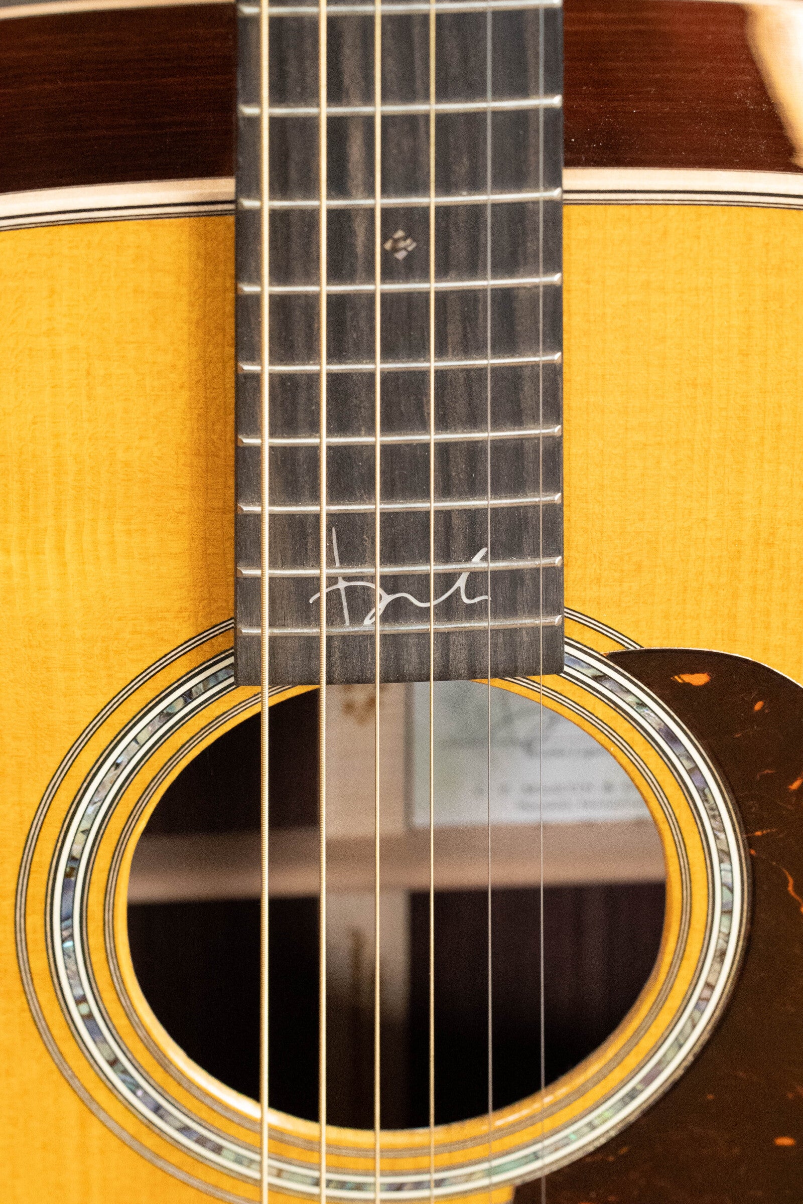 Close-up of a (Used) 2022 Martin Brook Ligertwood 000-28 Spruce/Rosewood OOO Acoustic Guitar’s fretboard and sound hole, featuring a white signature above the rosette. The natural finish and rosewood details showcase classic Martin & Co. craftsmanship.