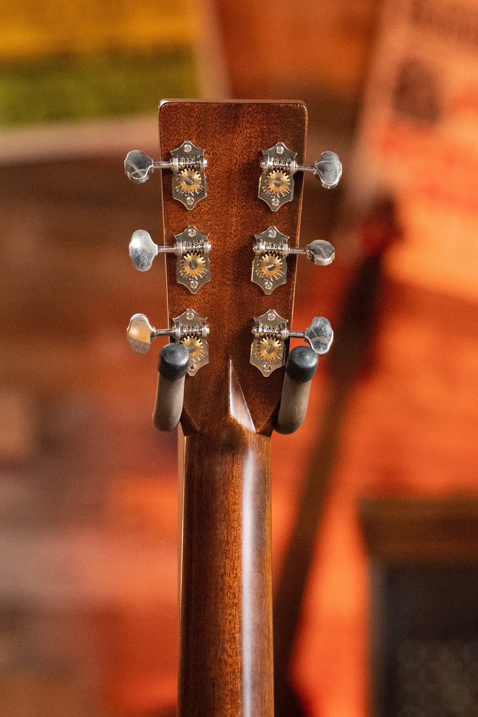 Close-up of a (Used) 2022 Martin Brook Ligertwood 000-28 Spruce/Rosewood OOO Acoustic Guitar by Martin & Co., showing the East Indian rosewood headstock with six tuning pegs against a blurred, warm-toned background.