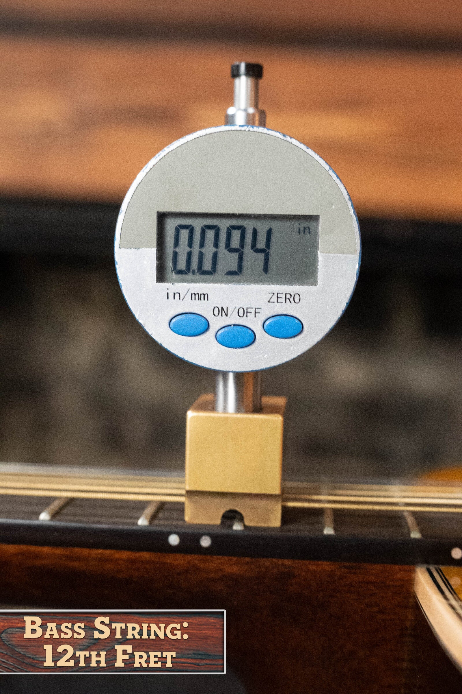 A digital gauge displays 0.094 as the height of a bass string at the 12th fret, with a wooden block on the fretboard like East Indian rosewood from a Martin & Co. (Used) 2022 Brook Ligertwood 000-28 Spruce/Rosewood OOO Acoustic Guitar. Label: Bass String: 12th Fret.