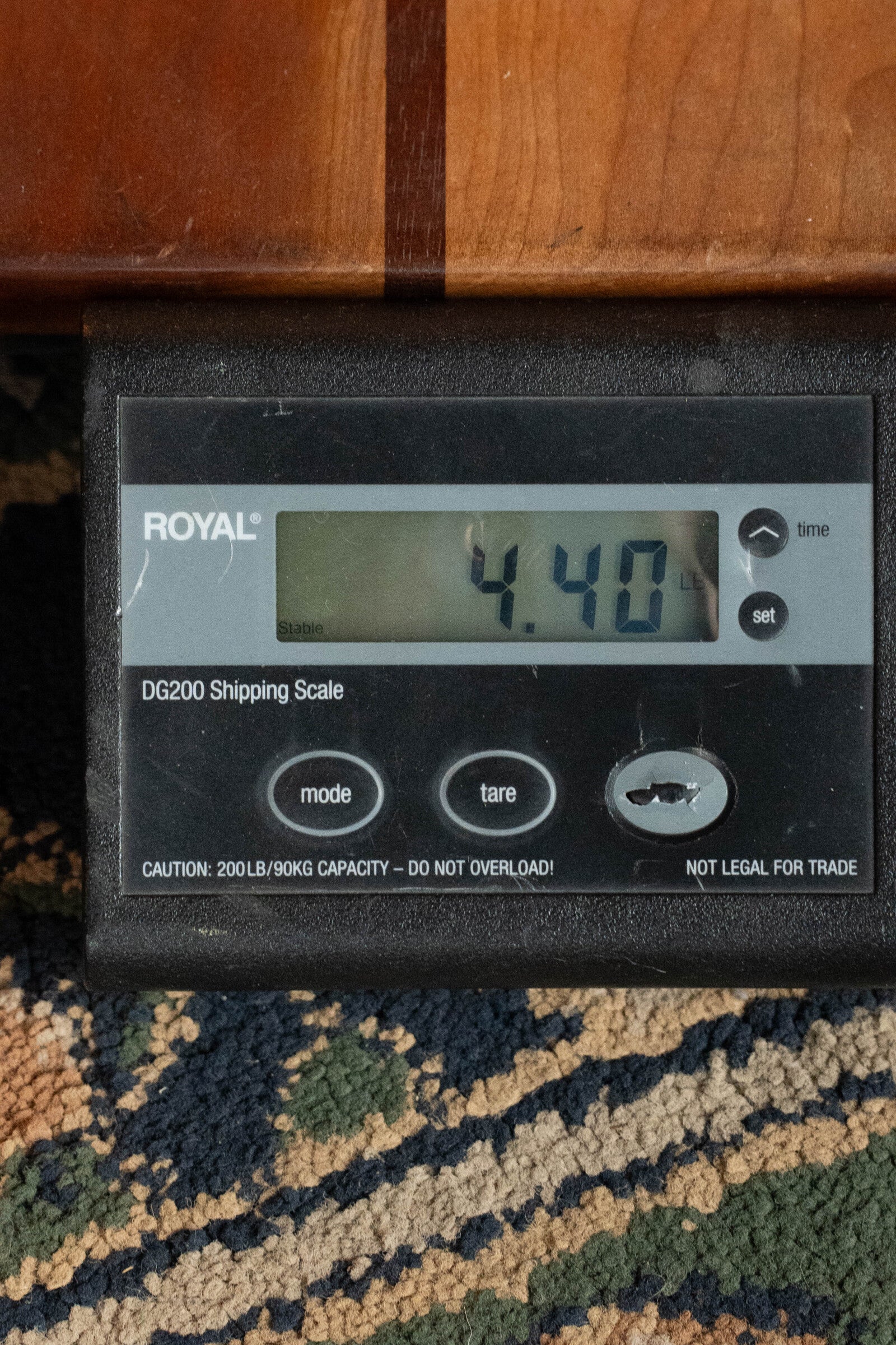 A digital scale shows 4.40 lbs beneath an Eastman Guitars (Used) 2023 E10OM-TC-SB Thermo-Cured Adirondack/Mahogany Sunburst Orchestra Model Acoustic Guitar #2966 on a colorful carpet.