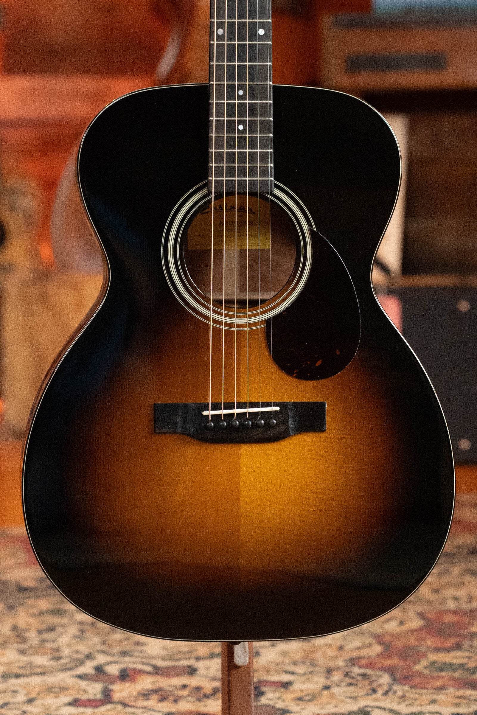 Close-up of a used 2023 Eastman Guitars E10OM-TC-SB Orchestra Model acoustic guitar (#2966) with a sunburst finish, thermo-cured Adirondack spruce top, mahogany back and sides, six strings, and tortoiseshell pickguard.