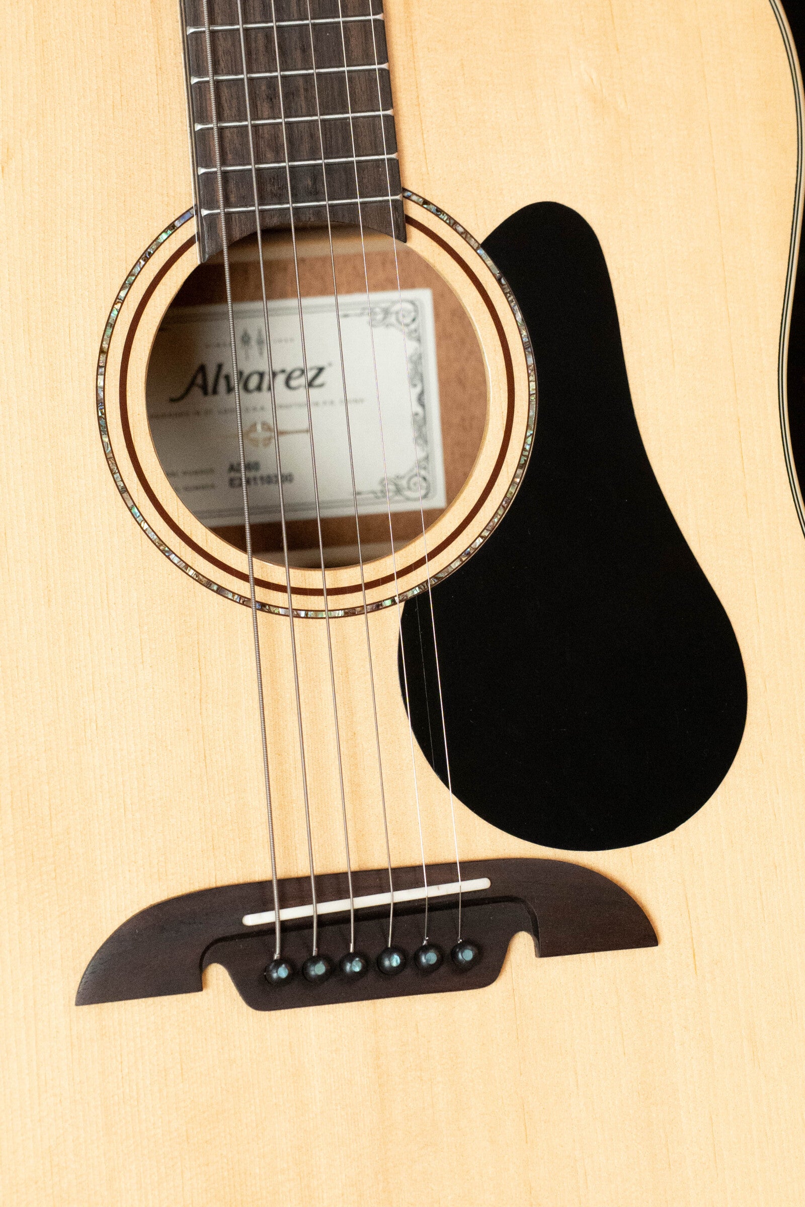 Close-up of a (Used) 2024 Alvarez AD60 Sitka/Mahogany Dreadnought Acoustic Guitar #0300 shows the sound hole, strings, bridge, pickguard, inner Alvarez label, and visible wood grain on the top.