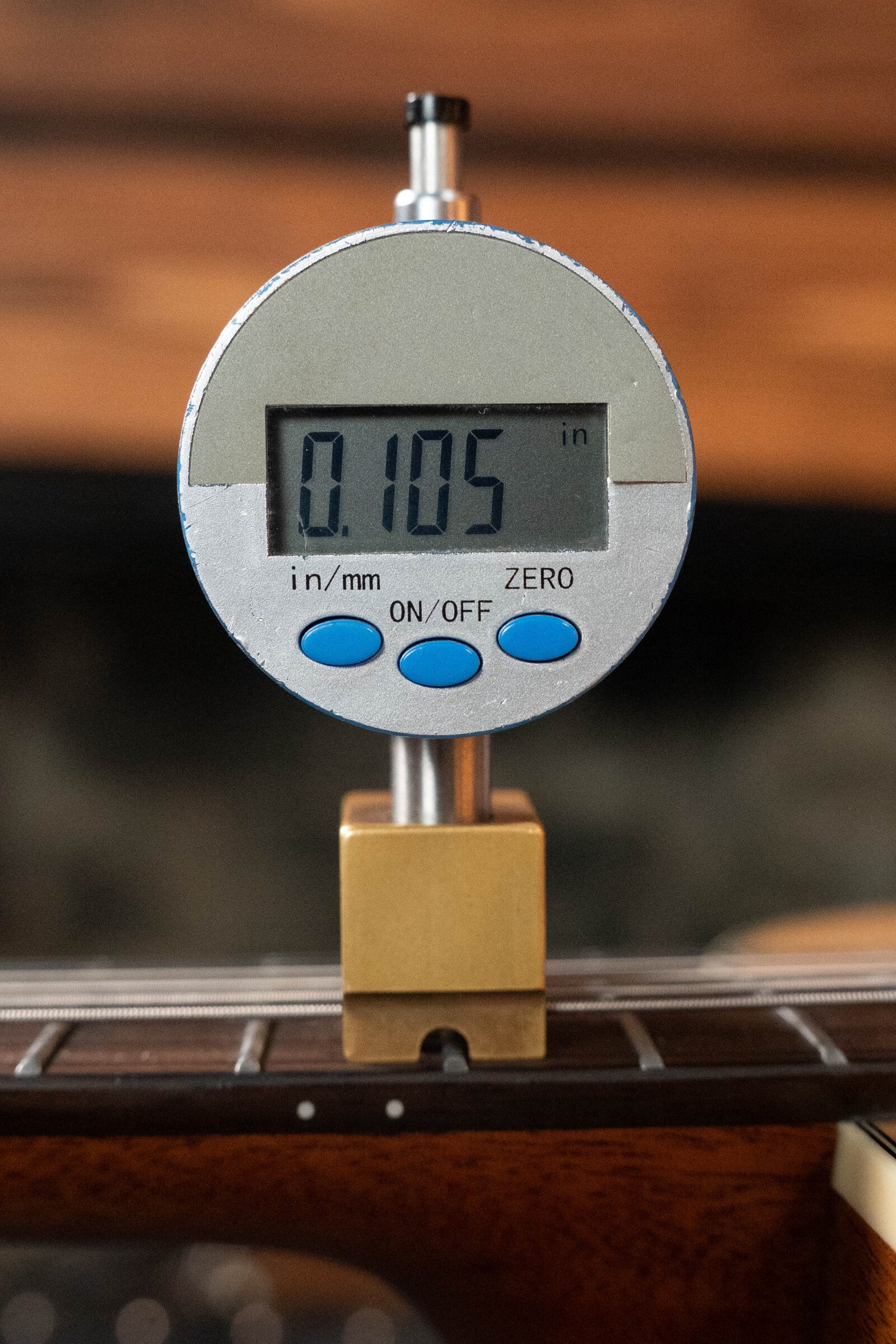 A digital gauge with blue buttons and a metal base shows a 0.105 gap above the strings on a (Used) 2024 Alvarez AD60 Sitka/Mahogany Dreadnought Acoustic Guitar #0300.