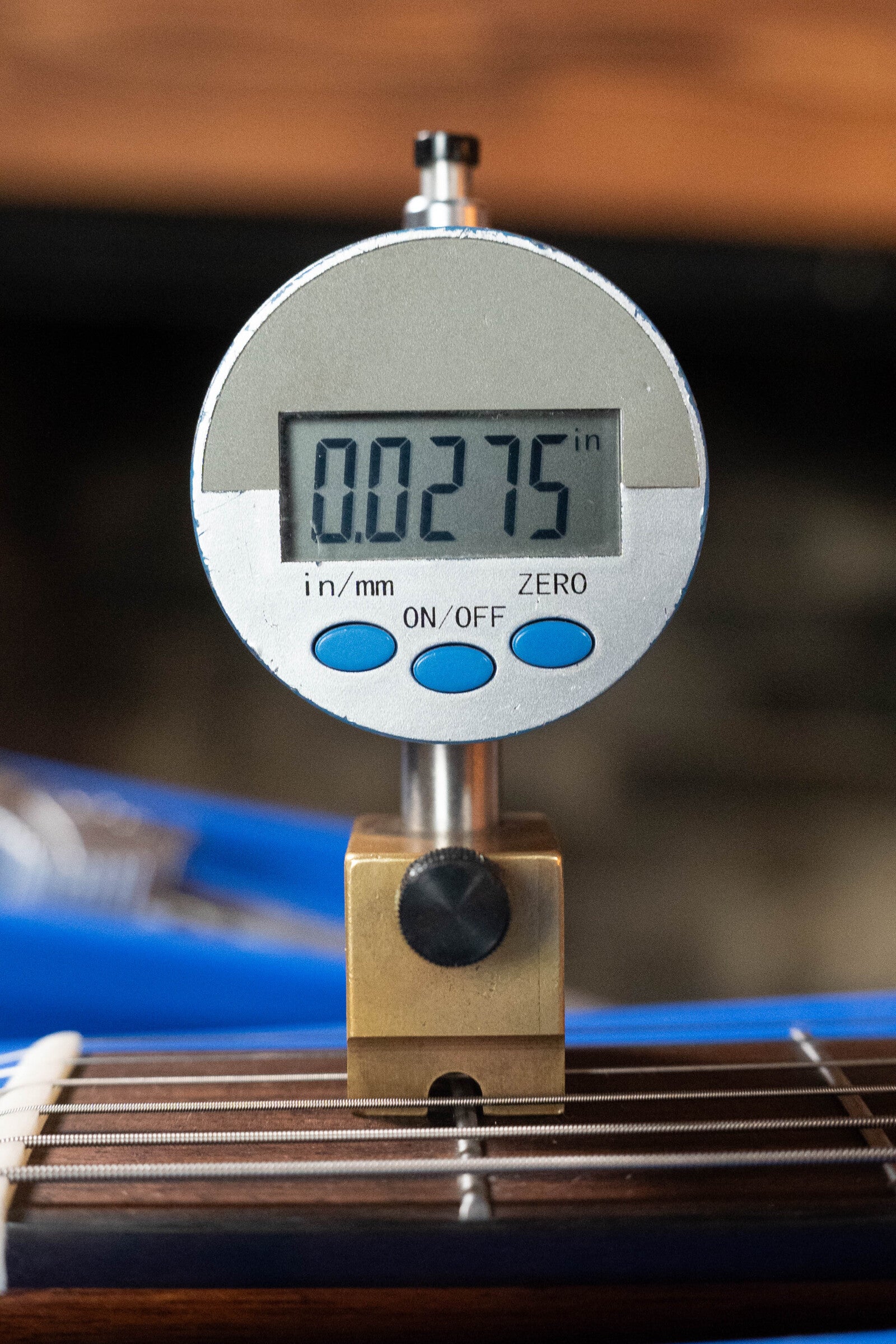 A digital gauge reads 0.0275 inches on the fretboard of a (Used) 2024 Alvarez AD60 Sitka/Mahogany Dreadnought Acoustic Guitar #0300, with metal strings visible below, by Alvarez.