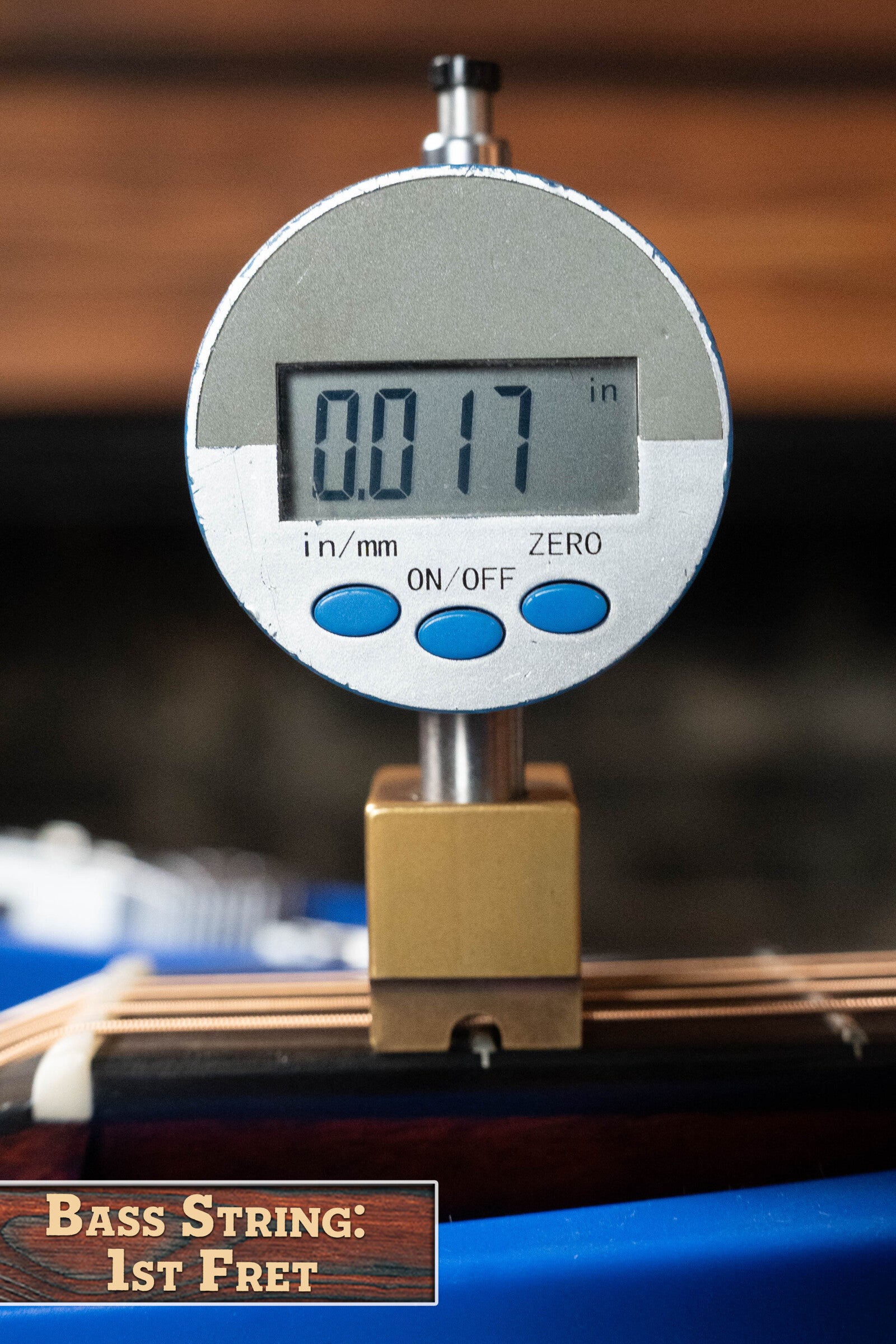 A digital gauge reads 0.017 inches, measuring the bass string height at the first fret—similar to precise setup on a (Used) 2024 Eastman Guitars E10OO-TC Thermo-Cure Adirondack/Mahogany Acoustic Guitar #0268.