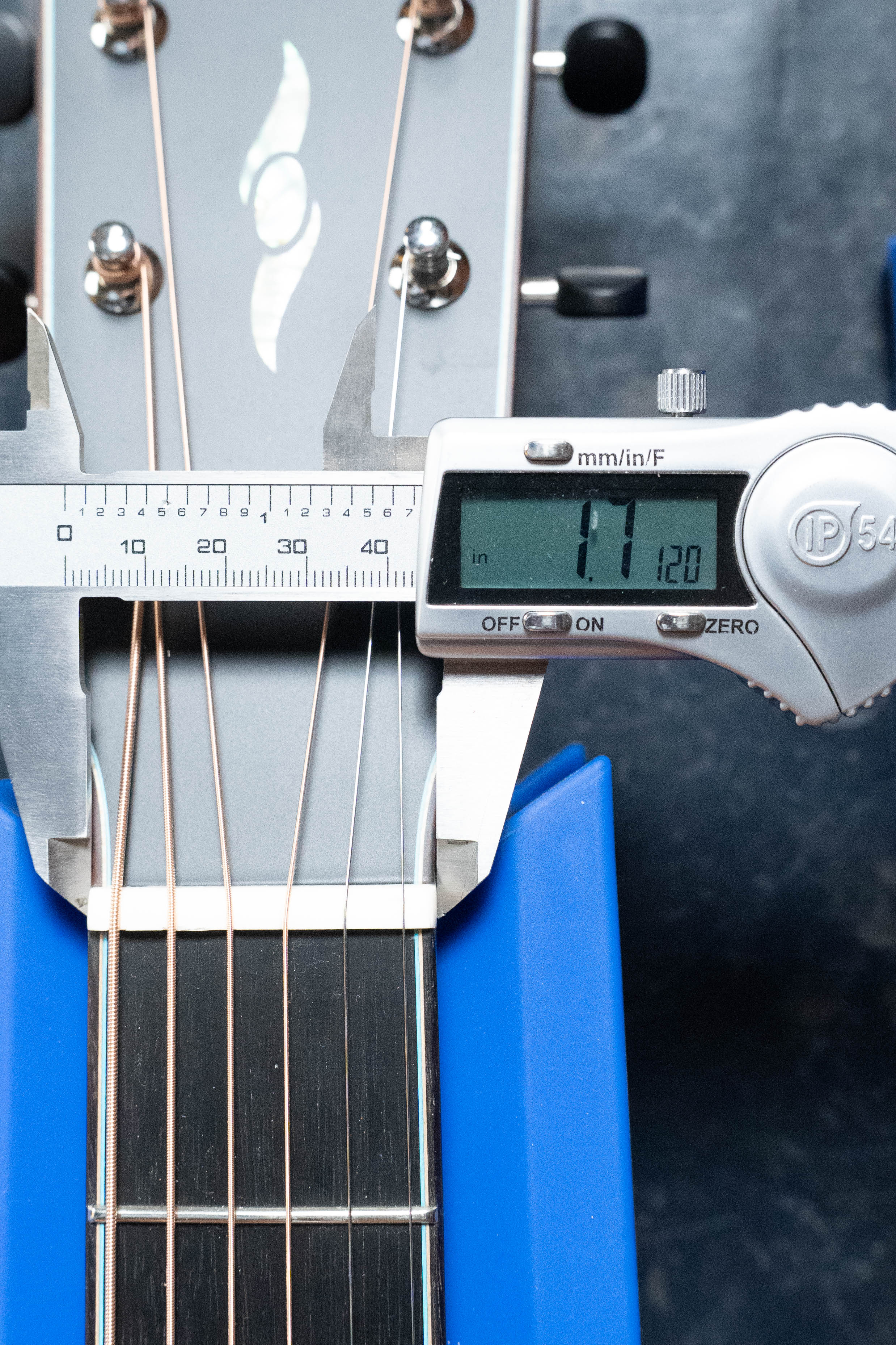 A digital caliper shows 44.20 mm when measuring the nut width of a (Used) 2025 Eastman L-OOSS-LTD-KOA Limited Edition All Koa Acoustic Guitar #9075 by Eastman Guitars, supported securely by blue rests.