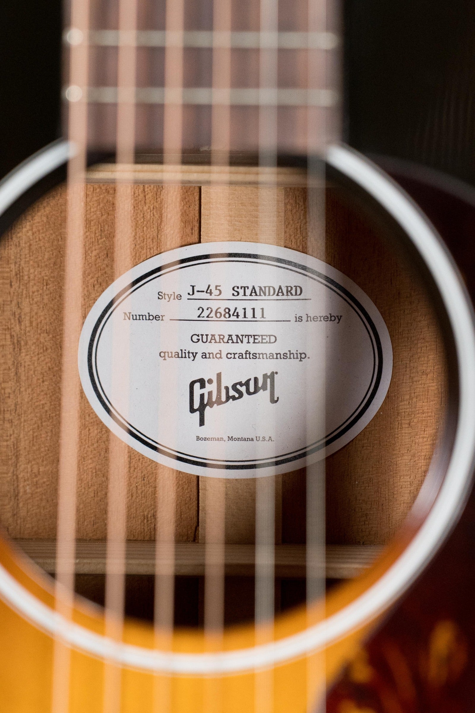 Close-up of a (Used) Gibson J45 Standard Sitka/Mahogany Round Shoulder Vintage Sunburst Dreadnought Guitar w/K&K Pickup #4111, highlighting the soundhole label with serial number and Gibson logo—showcasing quality craftsmanship.