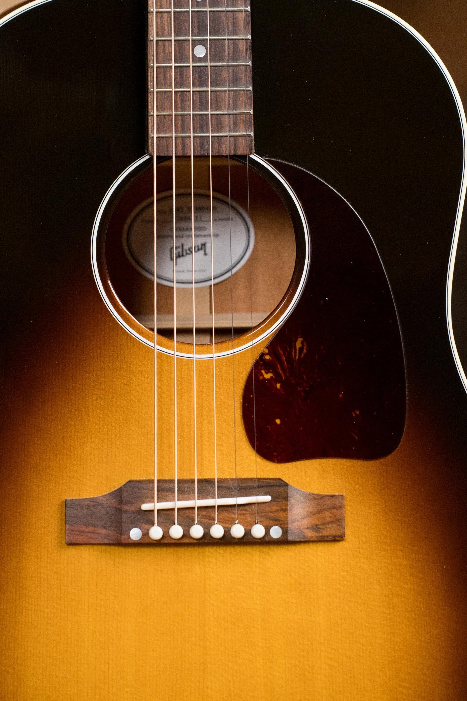 Close-up of a used Gibson J45 Standard Sitka/Mahogany Round Shoulder Dreadnought Guitar in Vintage Sunburst, showing strings, bridge, pickguard, and soundhole with visible Gibson logo. Includes K&K pickup.