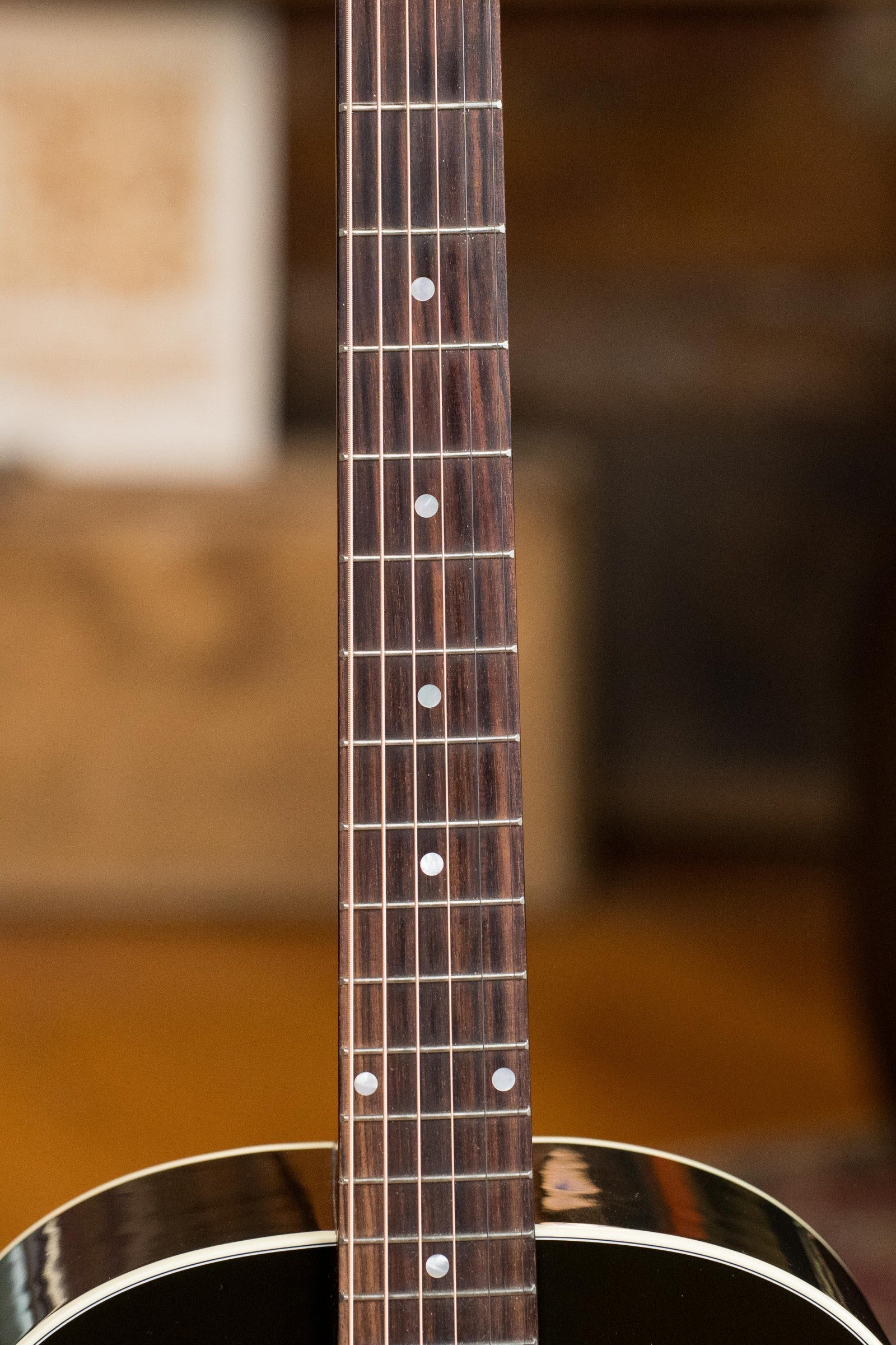 Close-up of a used Gibson J45 Standard Sitka/Mahogany neck and fretboard, showing metal frets and dot inlays, with the Vintage Sunburst dreadnought body partially visible against a blurred background. Model: #4111 w/K&K pickup.