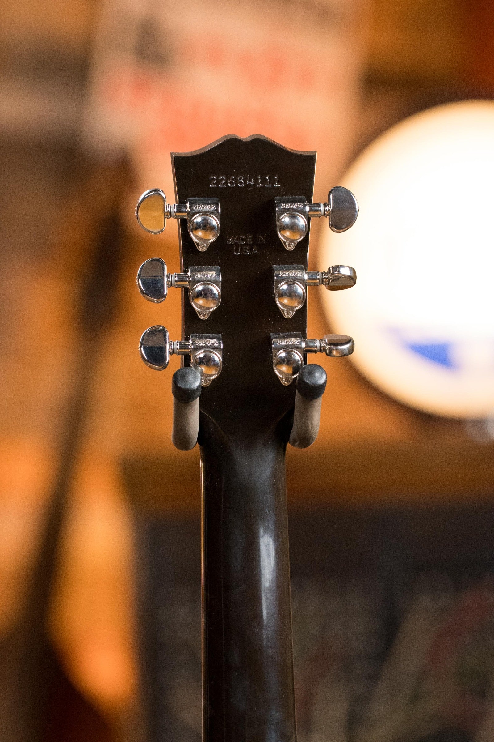 Close-up of the back of a (Used) Gibson J45 Standard Sitka/Mahogany Round Shoulder Vintage Sunburst Dreadnought Guitar w/K&K Pickup #4111 headstock, showing six tuners, serial number, and Made in USA text under warm indoor lighting.