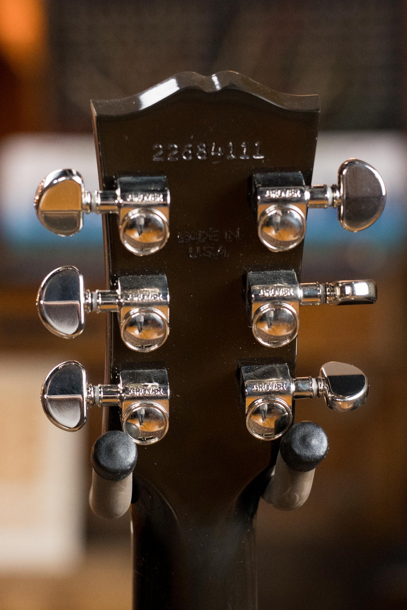 Close-up of the back of a (Used) Gibson J45 Standard Sitka/Mahogany Round Shoulder Vintage Sunburst Dreadnought Guitar w/K&K Pickup #4111, showing six chrome tuners, serial number, and MADE IN USA on the headstock against a blurred background.