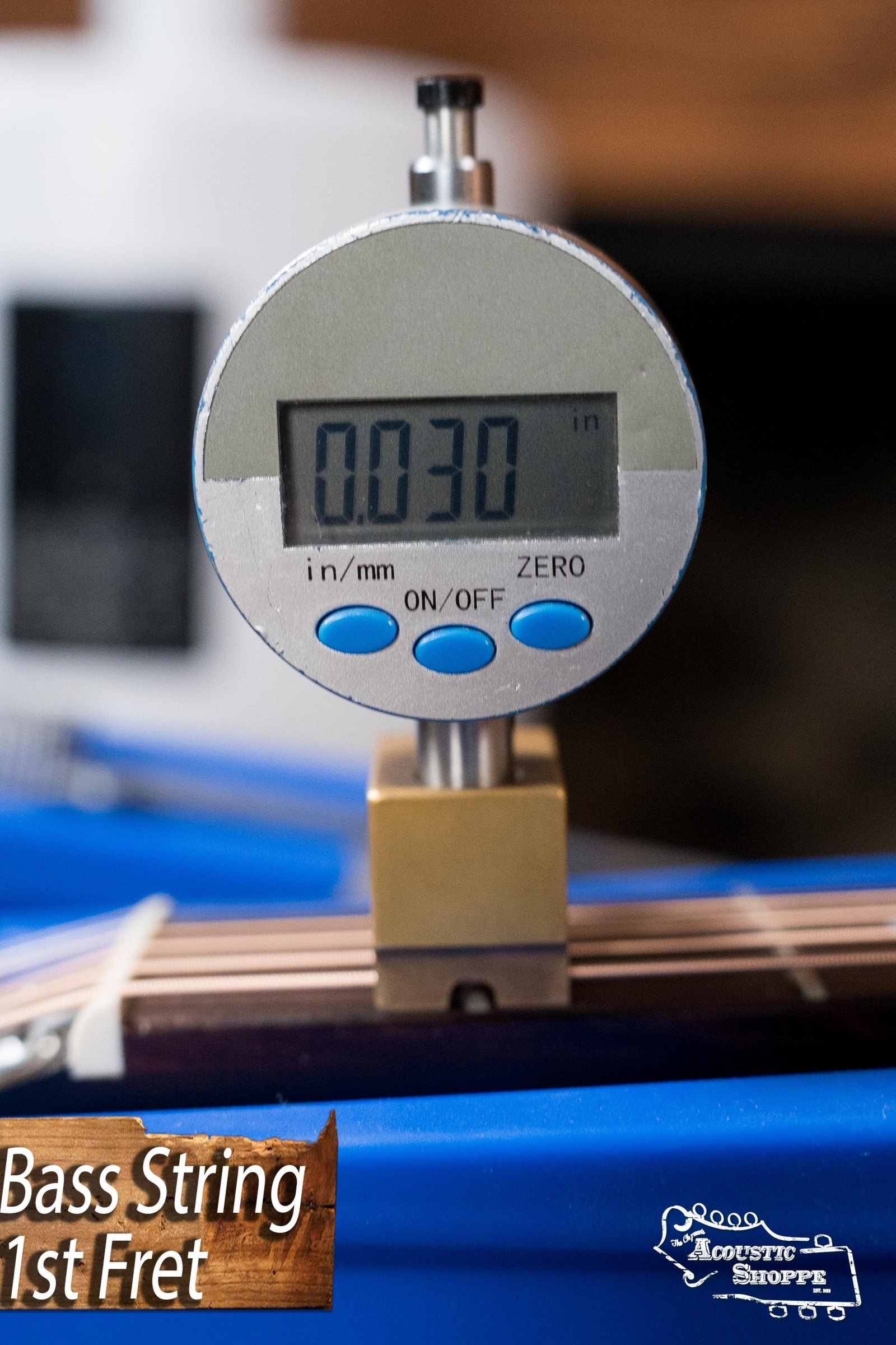 A digital caliper measures a string at the 1st fret of a (Used) Gibson J45 Standard Sitka/Mahogany Vintage Sunburst guitar, showing 0.030 inches; perfect for checking your Gibson acoustic from Acoustic Shoppe.