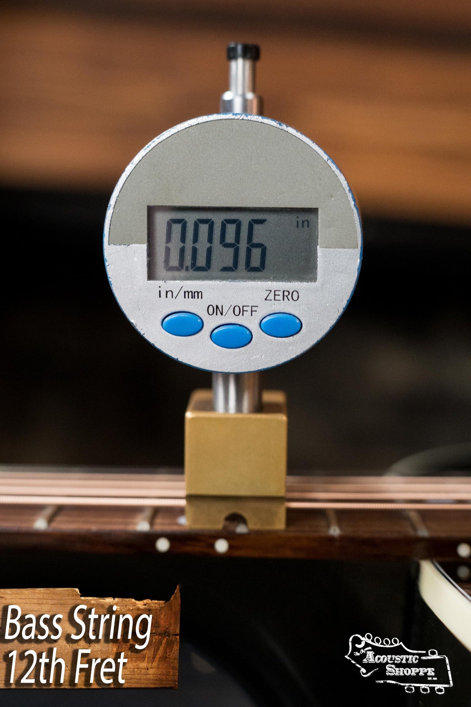 A digital caliper reads 0.096 inches measuring the bass string height above the 12th fret on a used Gibson J45 Standard Sitka/Mahogany Round Shoulder Vintage Sunburst Dreadnought guitar. Bass String 12th Fret and Acoustic Shoppe appear in the corners.