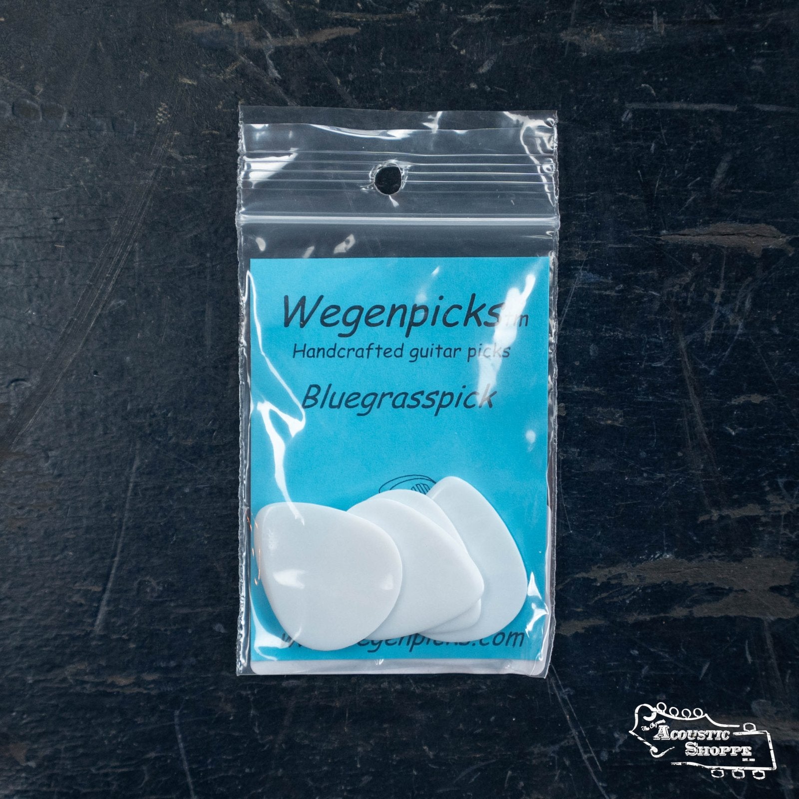 A Wegen Picks NH140 Bluegrass Acoustic Guitar Pick No Holes pack contains four white, handcrafted 1.4mm picks in clear packaging with a blue insert—perfect for boutique guitars or acoustic guitar accessories.