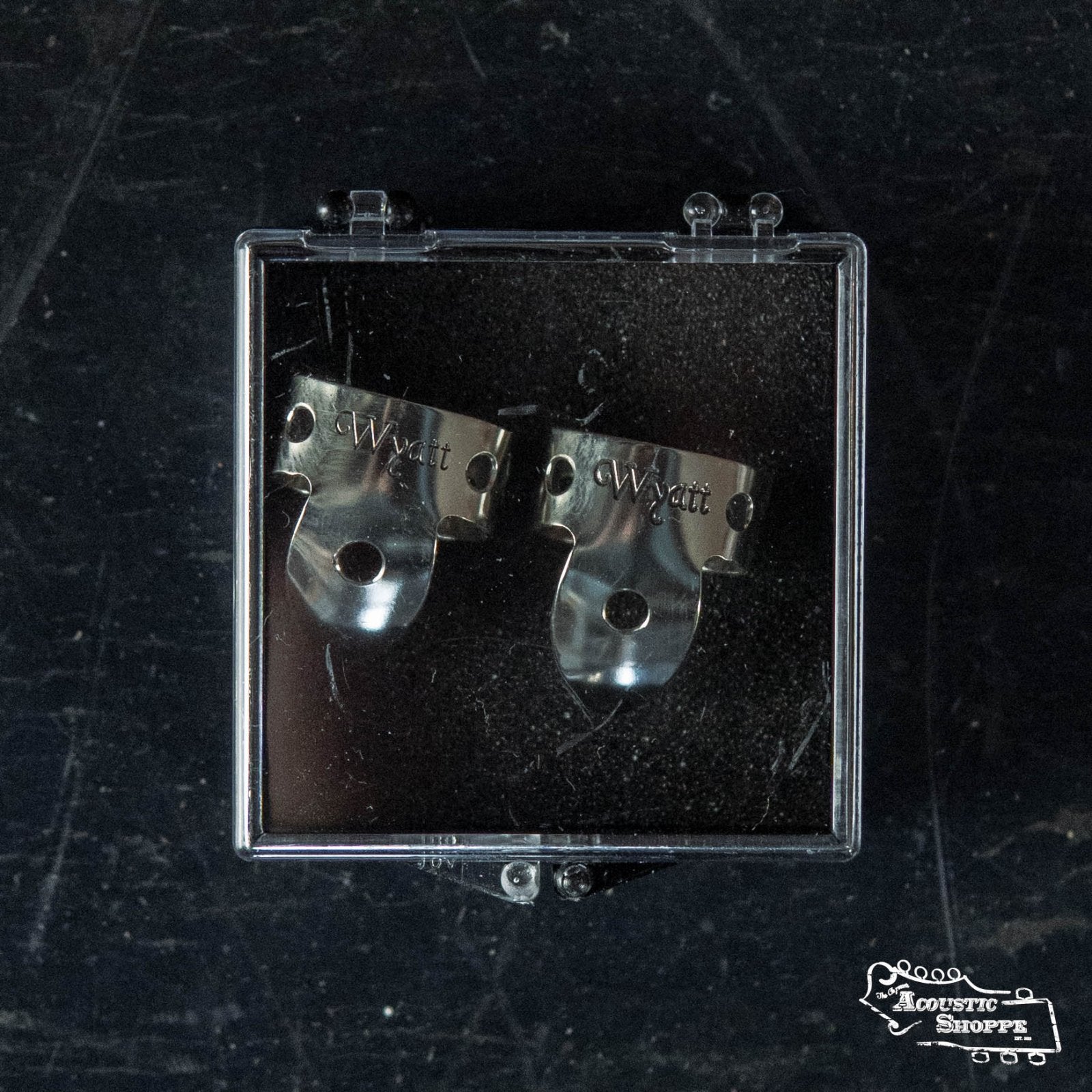 A pair of Wyatt Custom Banjos Finger Picks by Wyatt Custom Banjos are displayed in a clear plastic case on a dark surface, with The Acoustic Shoppe logo visible, reminiscent of classic Pre-War National Finger picks.