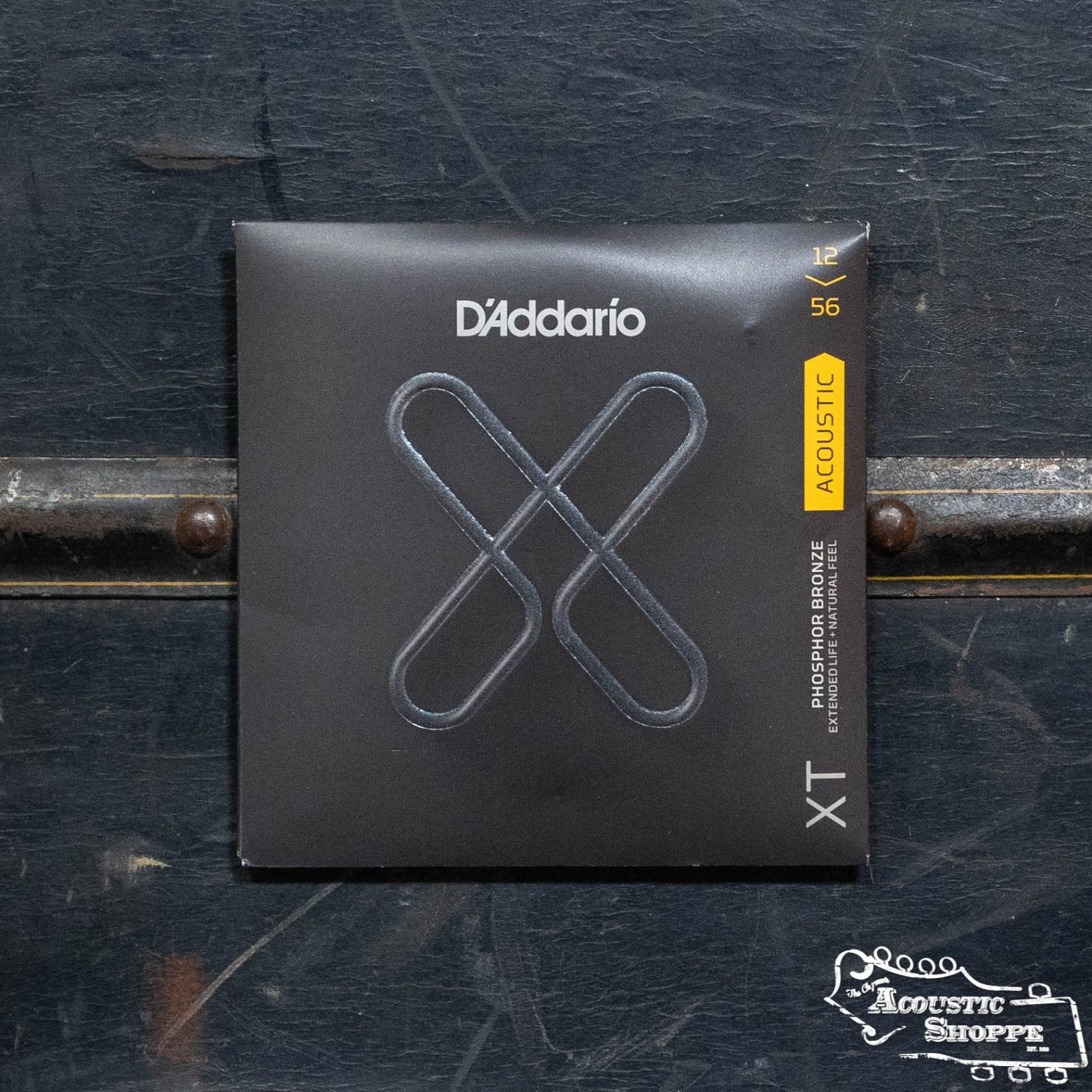 D'Addario XTAPB1256 Phosphor Bronze Light/Medium Acoustic Guitar Set comes in a minimalist black square pack with a silver "XT" graphic, showcasing long-lasting strings on a dark, textured background.