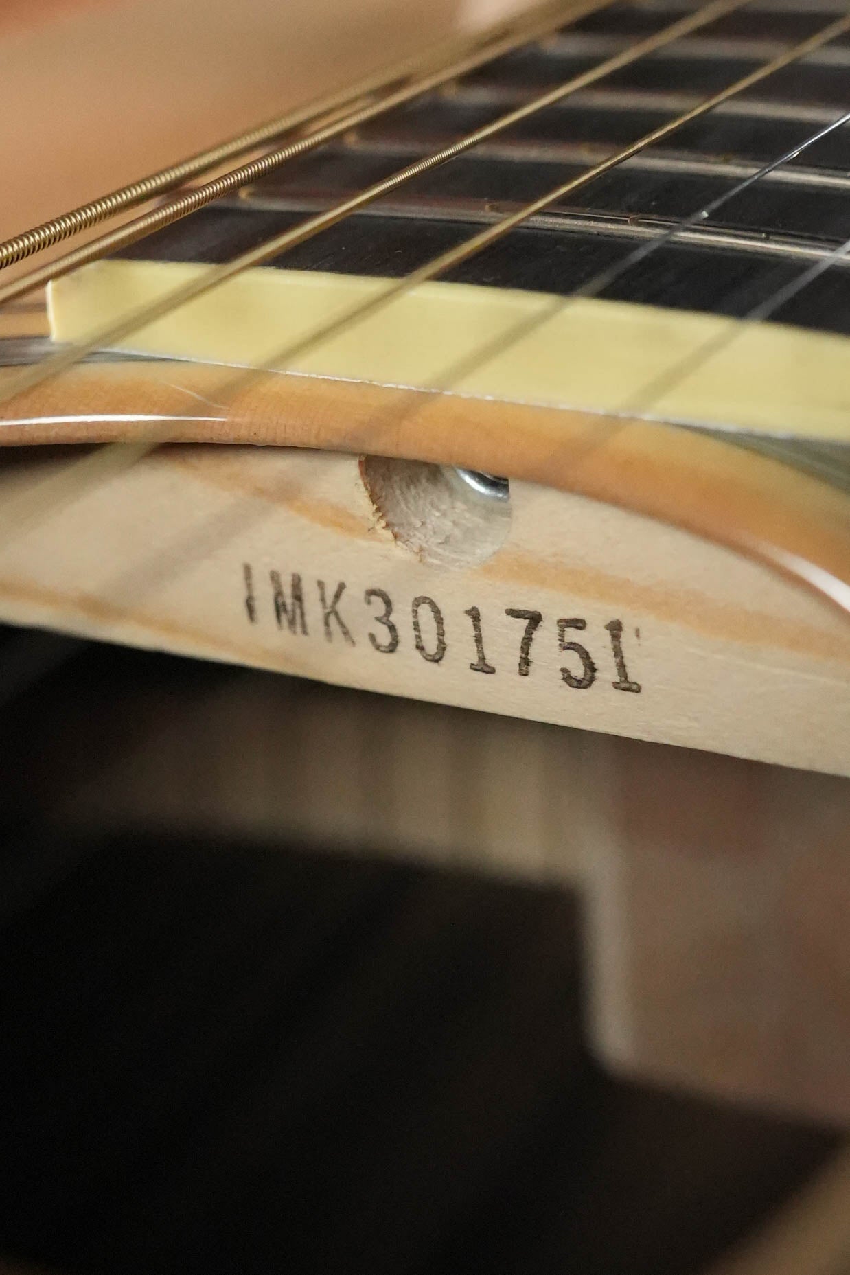 Close-up of the Yamaha FS830 Concert Acoustic Guitar #1751 by Yamaha, focusing on the neck with serial number IMK301751 beneath the dark fretboard and metal strings, showcasing its solid spruce top craftsmanship.
