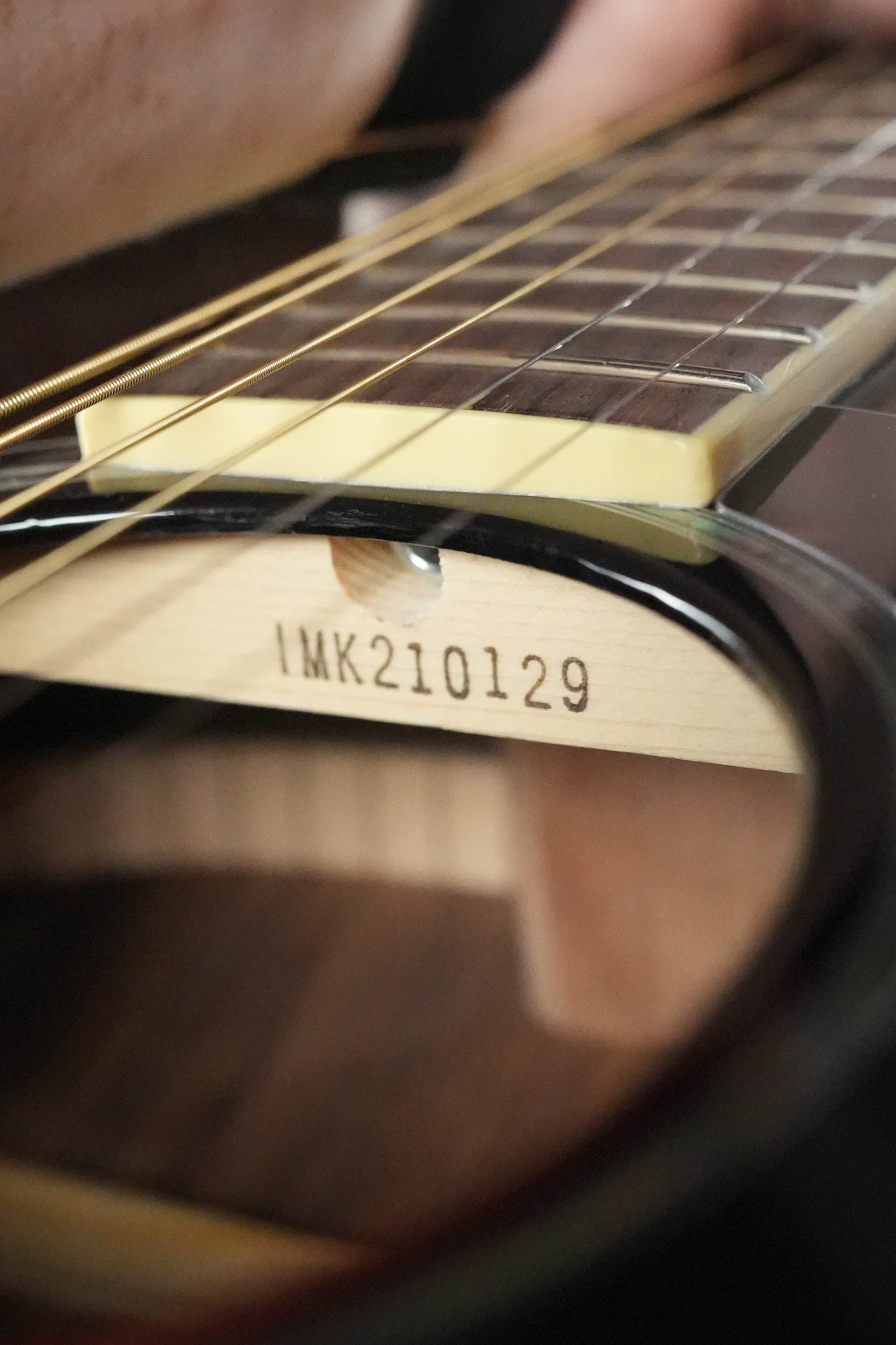 Close-up of a Yamaha FS830 TBS Tobacco Sunburst Concert Acoustic Guitar #0129 showing its strings, fretboard, solid spruce top, and the serial number 0129 inside the soundhole.