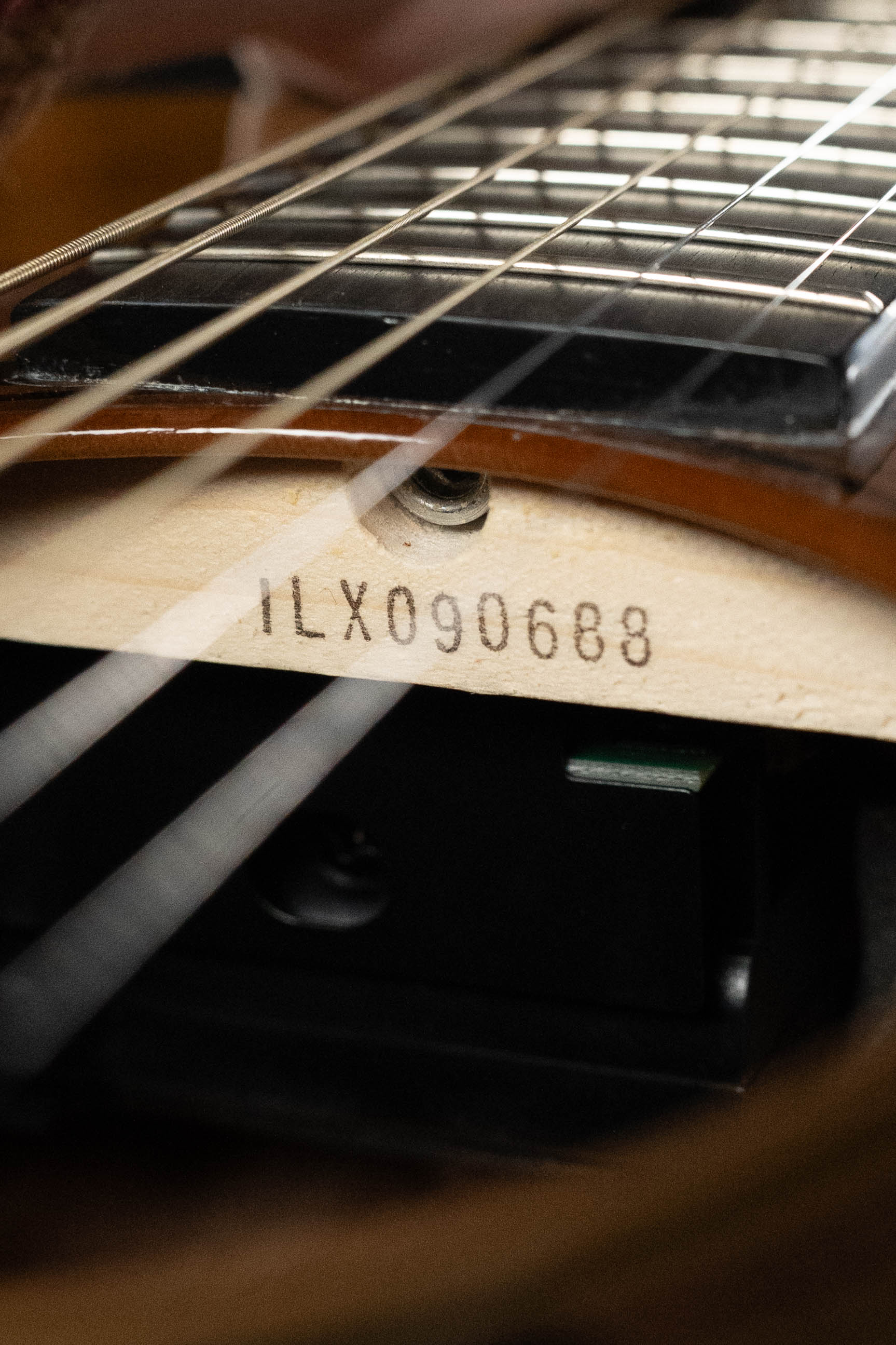 Close-up of a Yamaha TAG3C-SDB Sandburst Dreadnought Guitar neck showing serial #0688 stamped below the strings, with part of the fretboard and pickups visible. Features Sitka/Mahogany body and NEWEST TransAcoustic System.