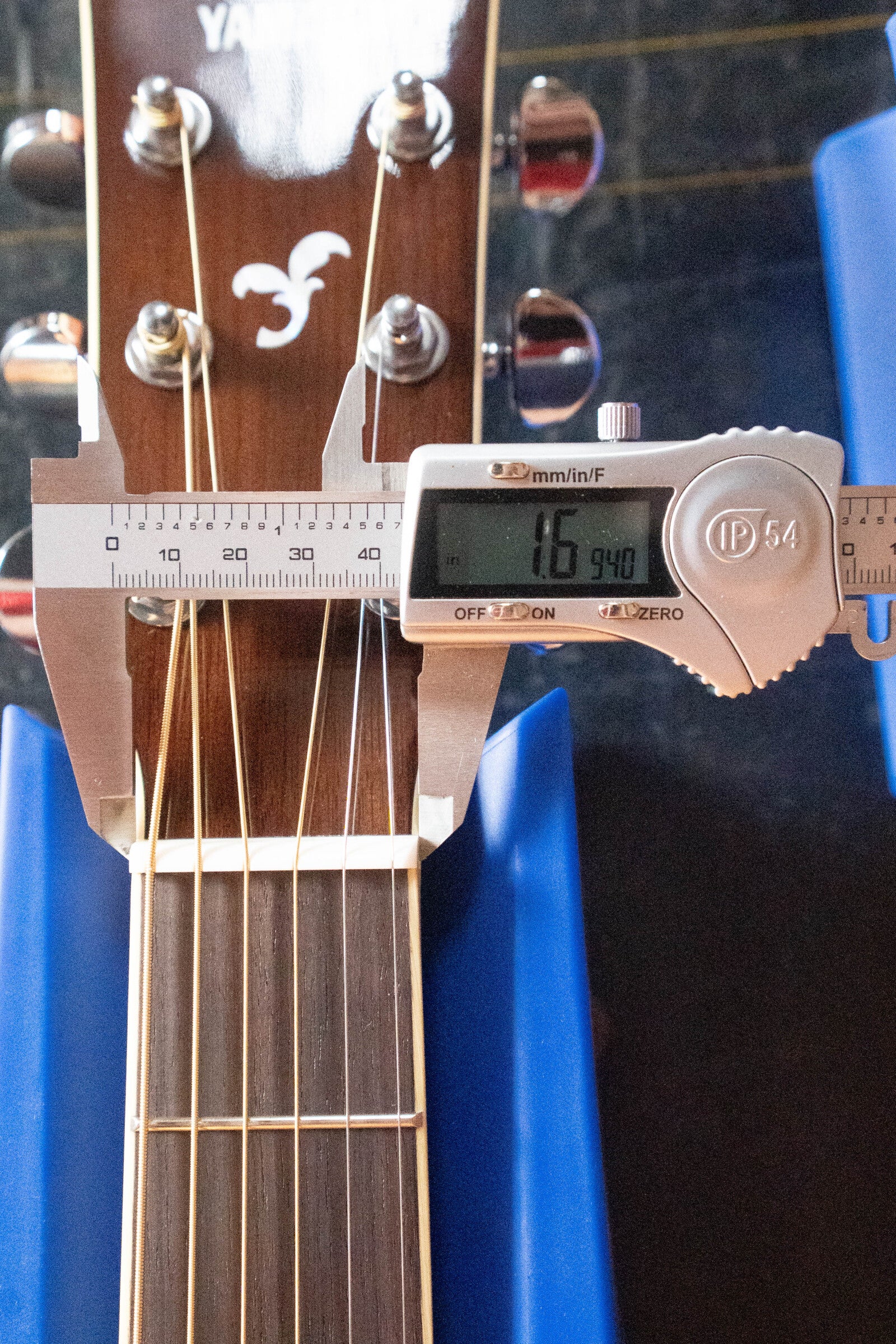 A digital caliper measures the nut width of the Yamaha FG830 Spruce/Laminate Rosewood Natural Dreadnought Acoustic Guitar #0562 at 16.94 mm, with the headstock, tuning pegs, and strings visible as it rests on blue supports.