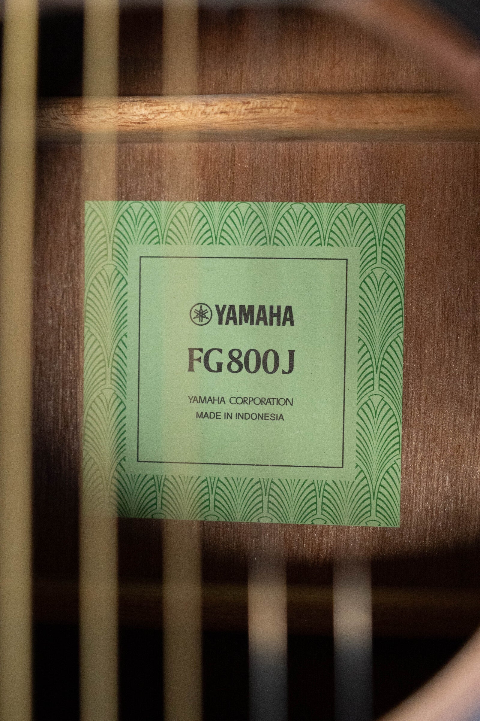 A close-up of the Yamaha GigMaker Deluxe Acoustic Pack - Natural Finish #8229 label inside a dreadnought guitar, with visible strings in the foreground—ideal for acoustic guitar beginners.