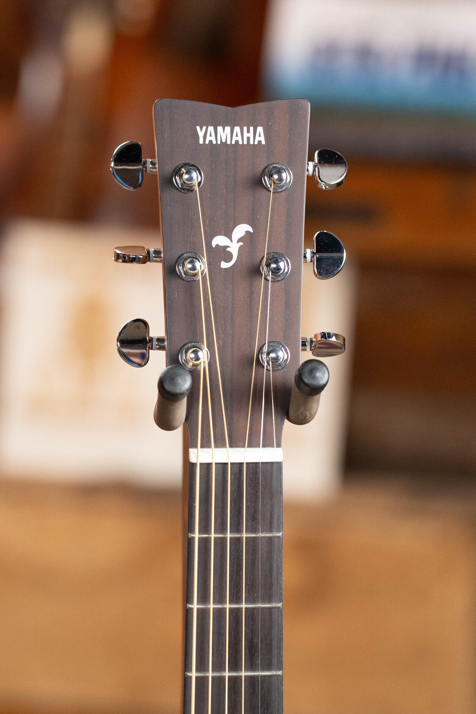Close-up of the headstock on the Yamaha GigMaker Deluxe Acoustic Pack in natural finish, highlighting tuning pegs, strings, and Yamaha logo—ideal for beginners starting their acoustic guitar journey.